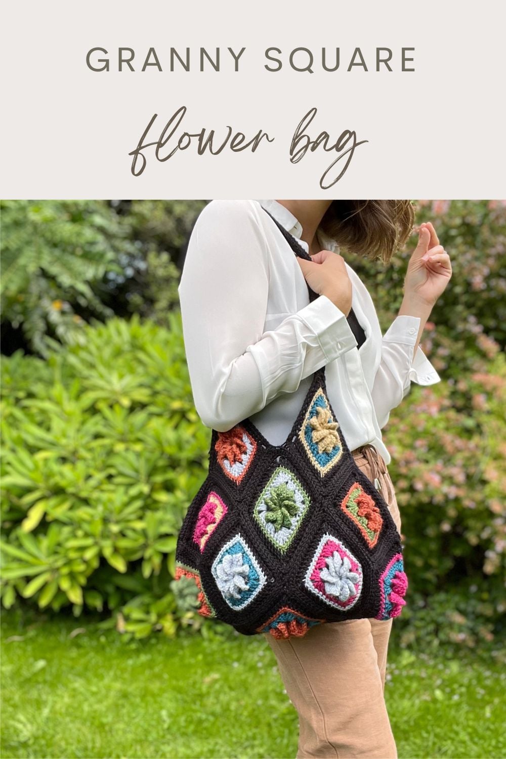 A person outdoors holds a vibrant Granny Square Bag Crochet, made of colorful granny squares with flower motifs, slung over their shoulder.