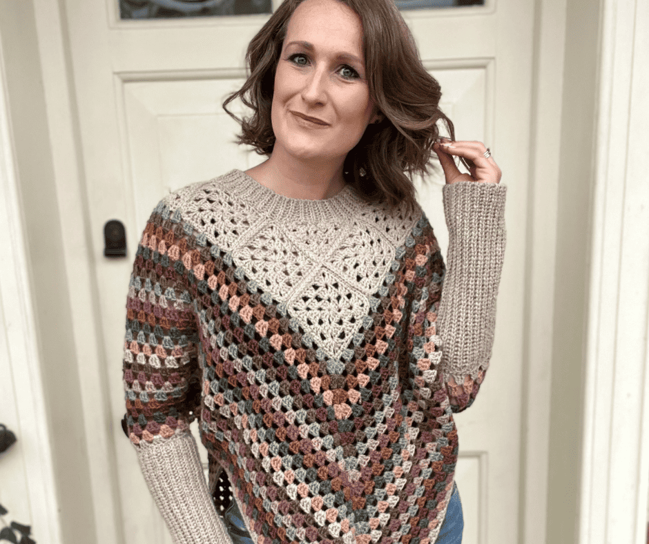 A woman wearing a crochet sweater and jeans.
