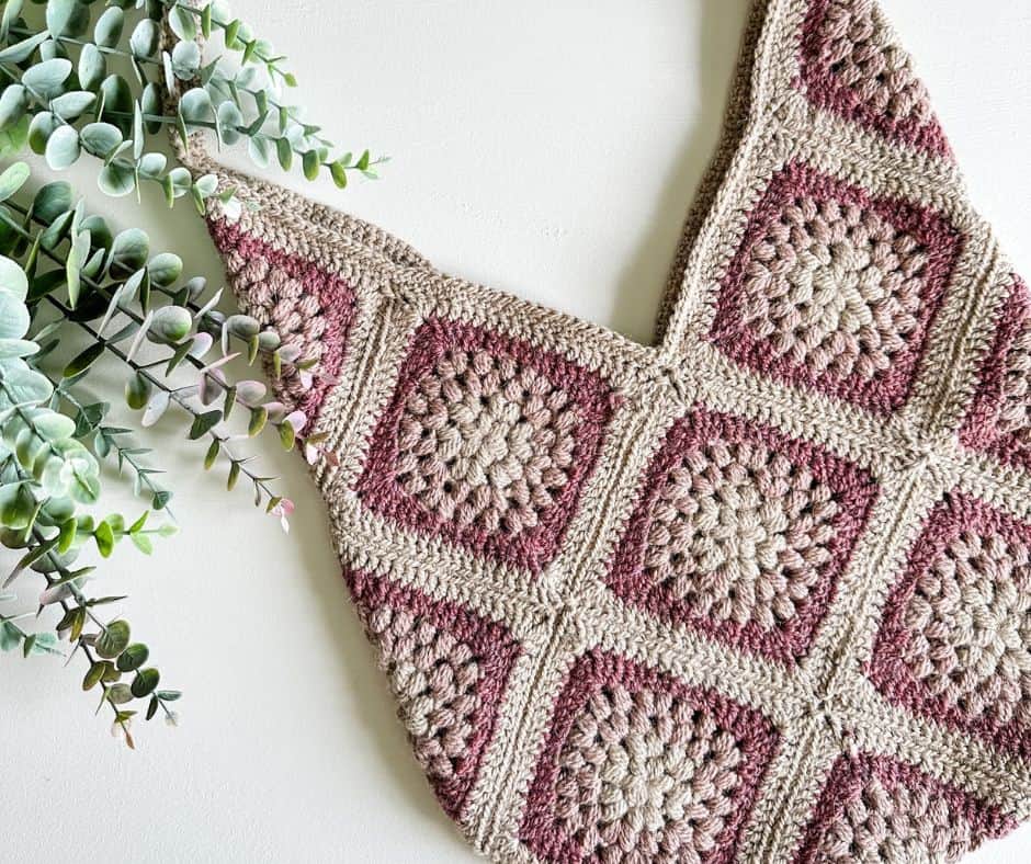A crocheted bag with pink and brown squares.
