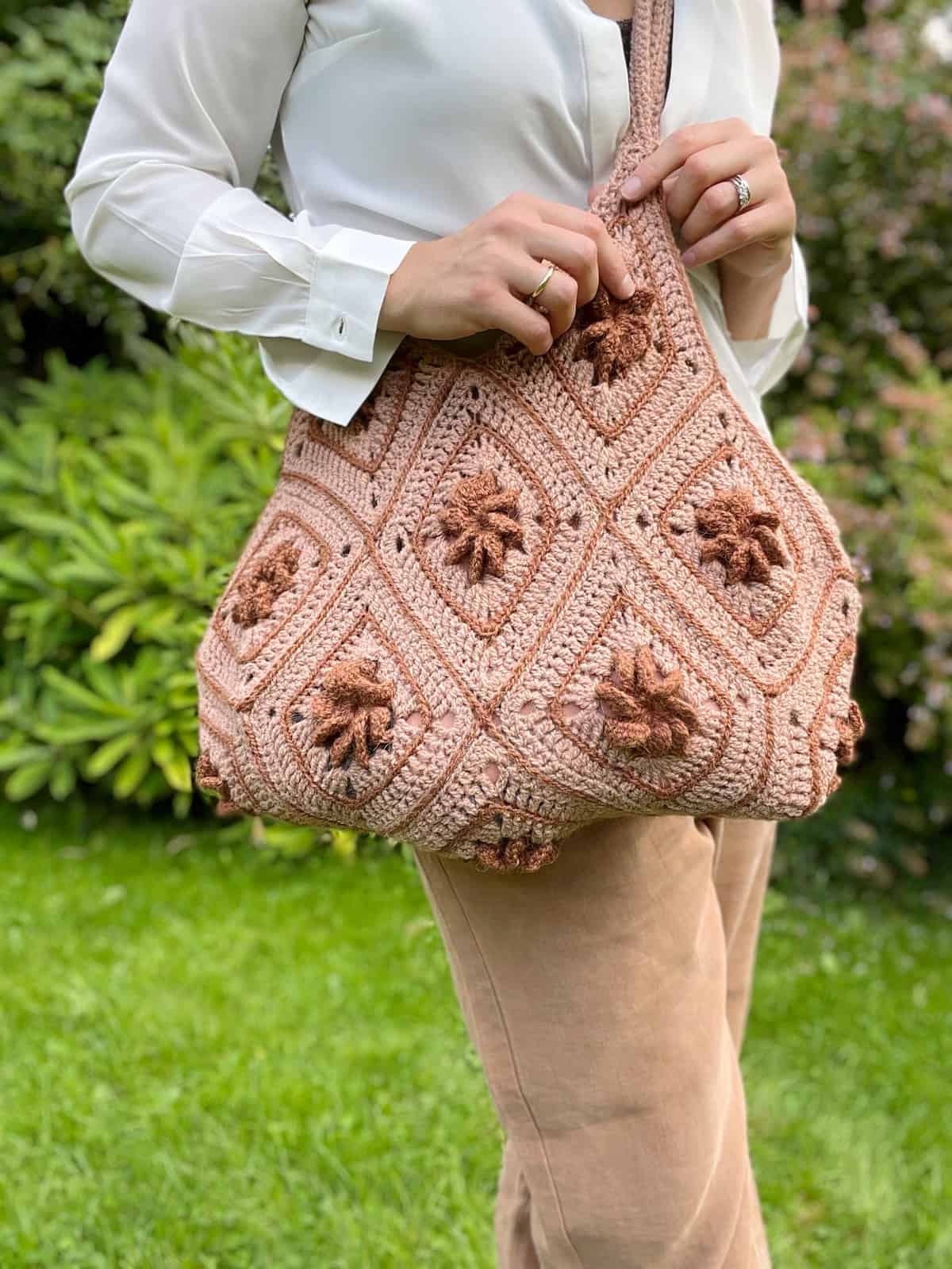 A woman holding a pink crocheted bag.