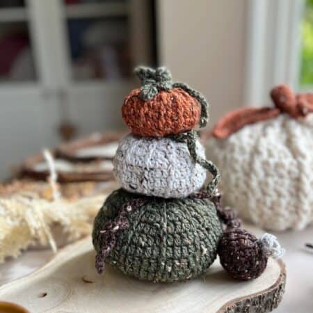 A stack of crocheted pumpkins on a wooden table.