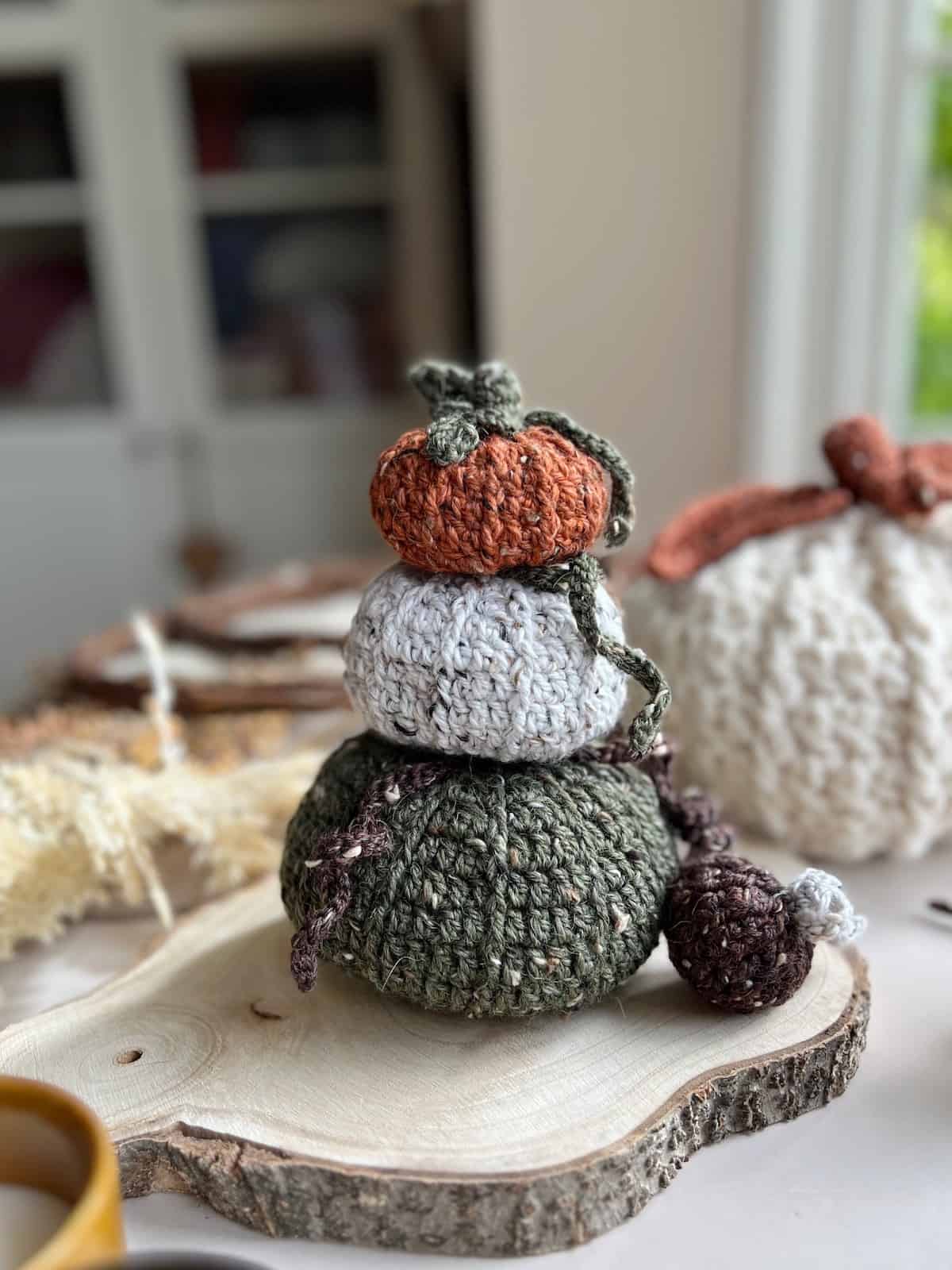 A stack of crocheted pumpkins on a wooden table.