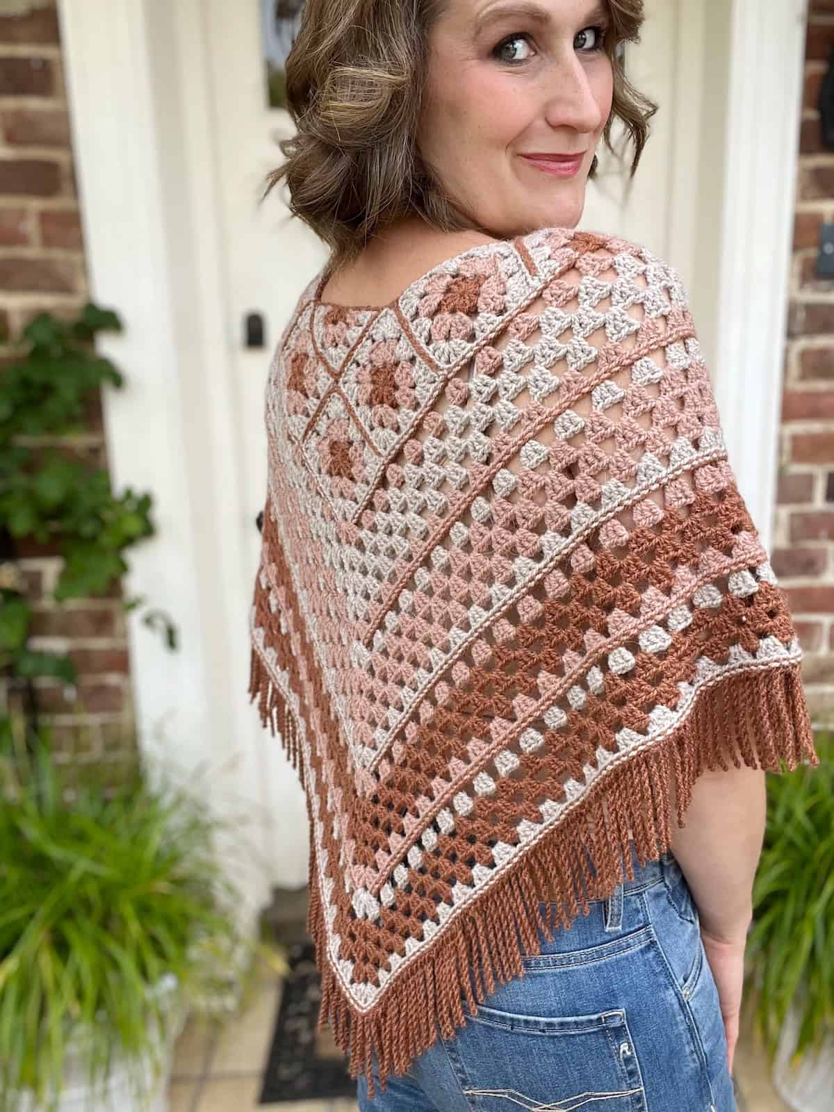 The back of a woman wearing a crocheted poncho.