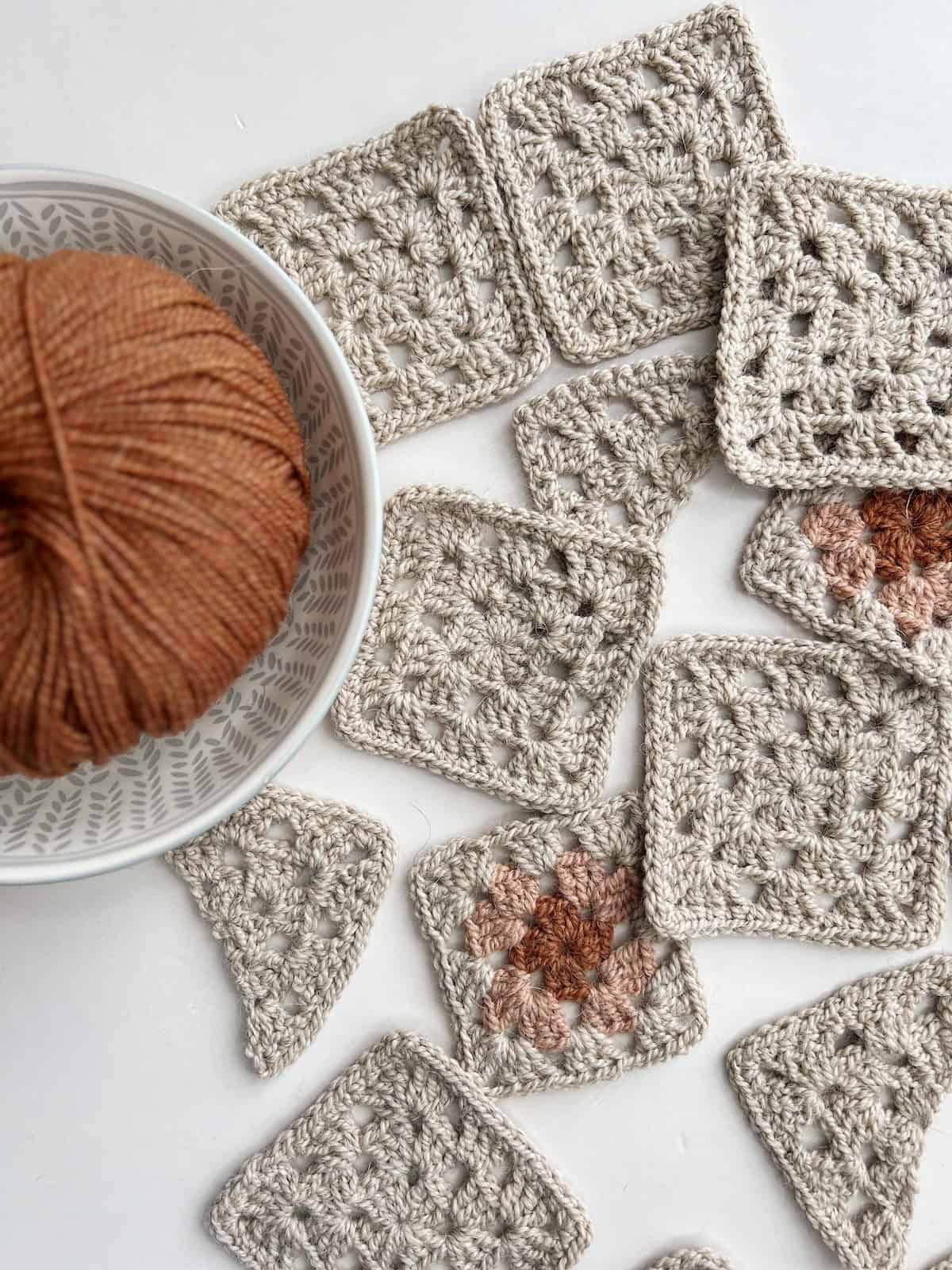 Crocheted squares with a ball of yarn next to them.