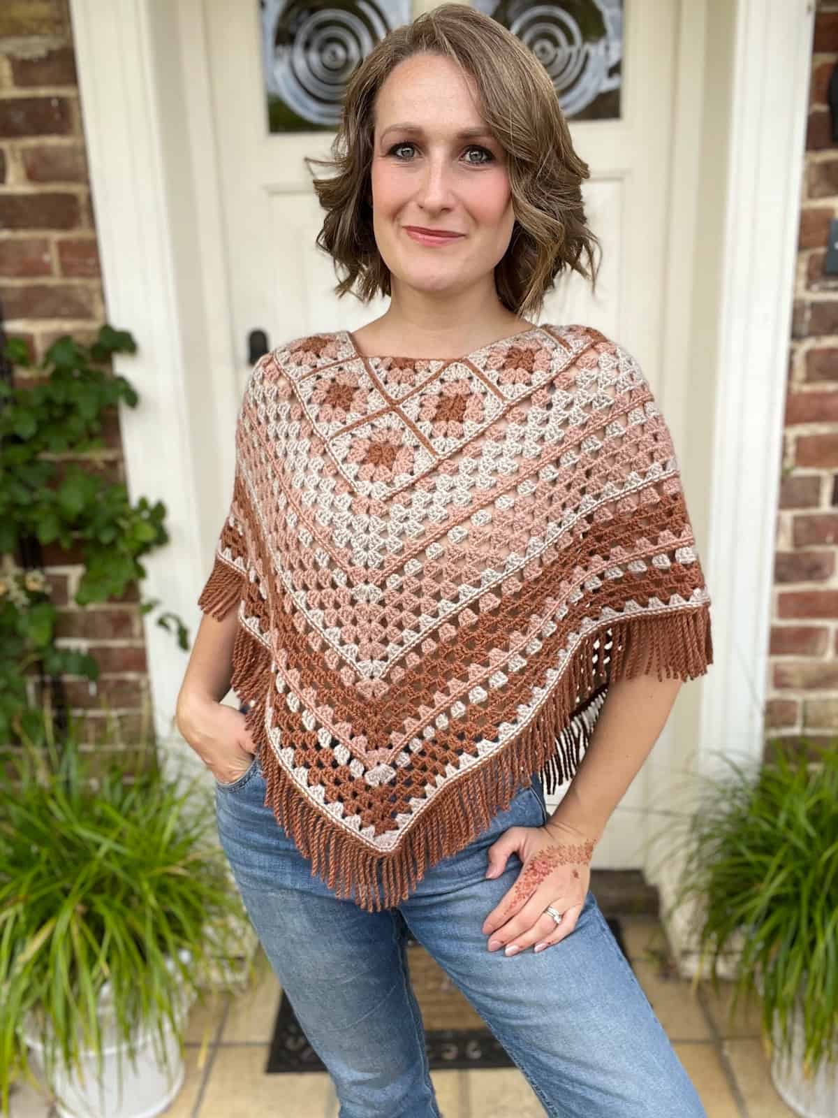 A woman wearing jeans and a crocheted poncho.