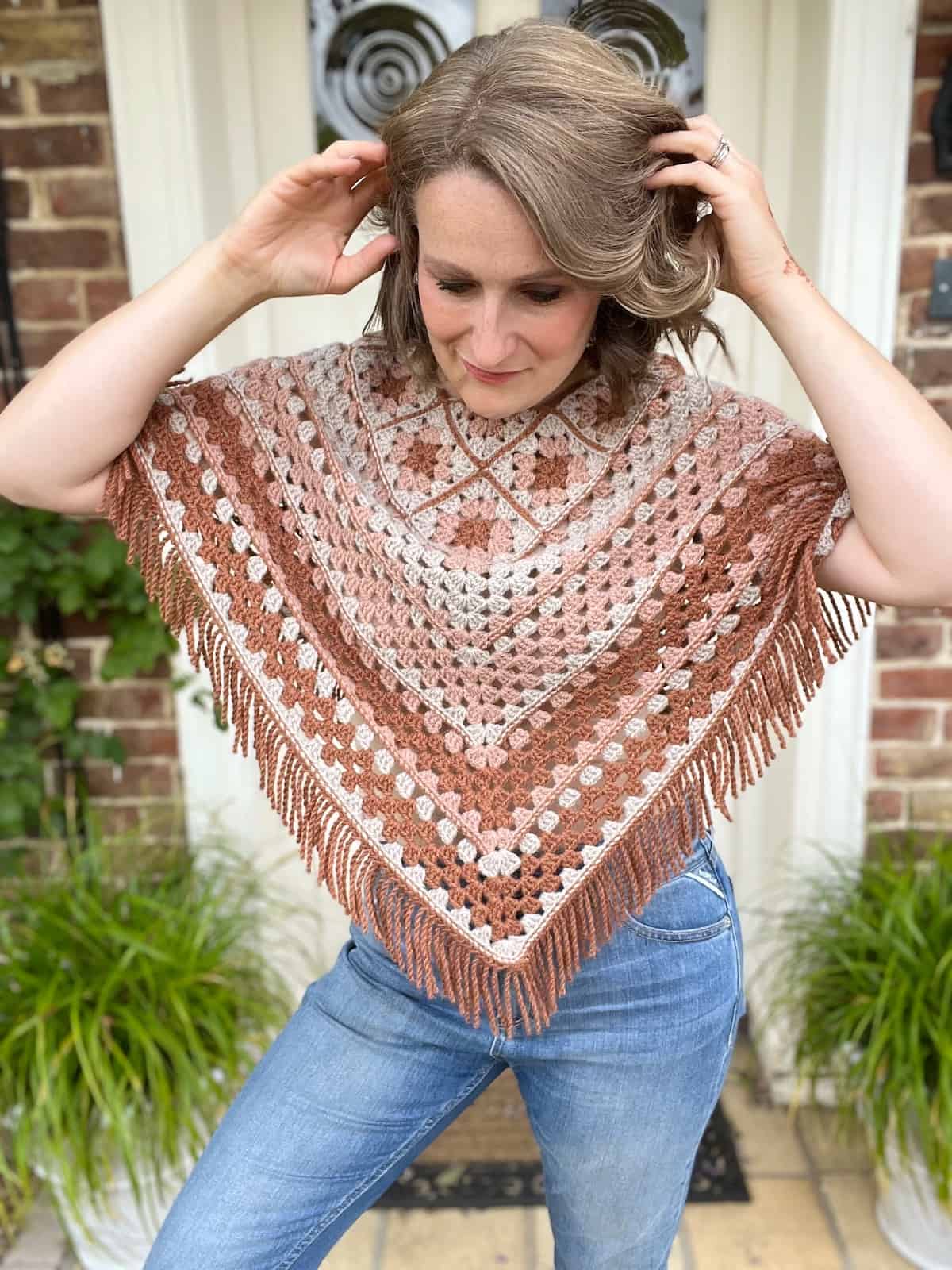 A woman wearing jeans and a crocheted poncho.