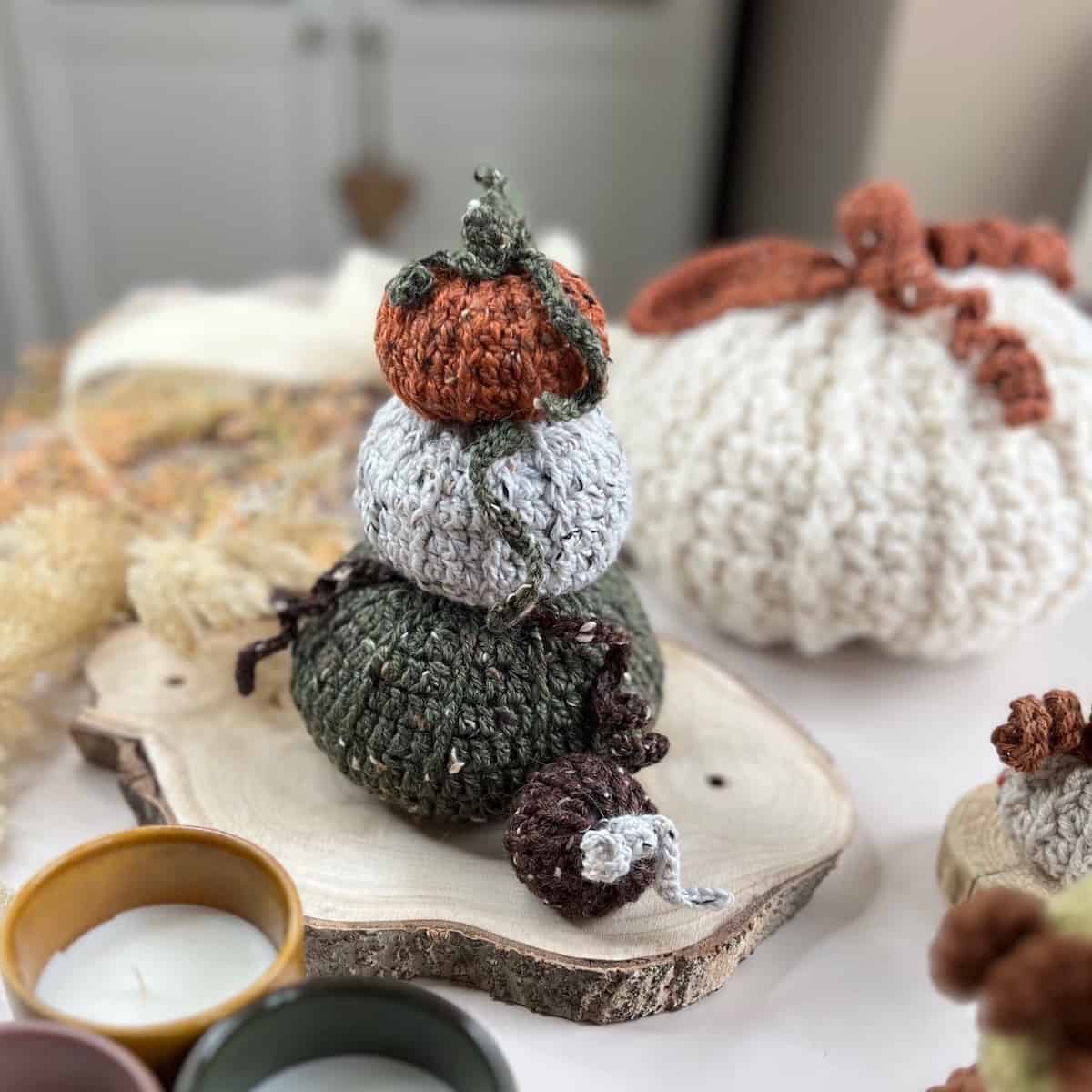 A stack of crocheted pumpkins on a wooden table.