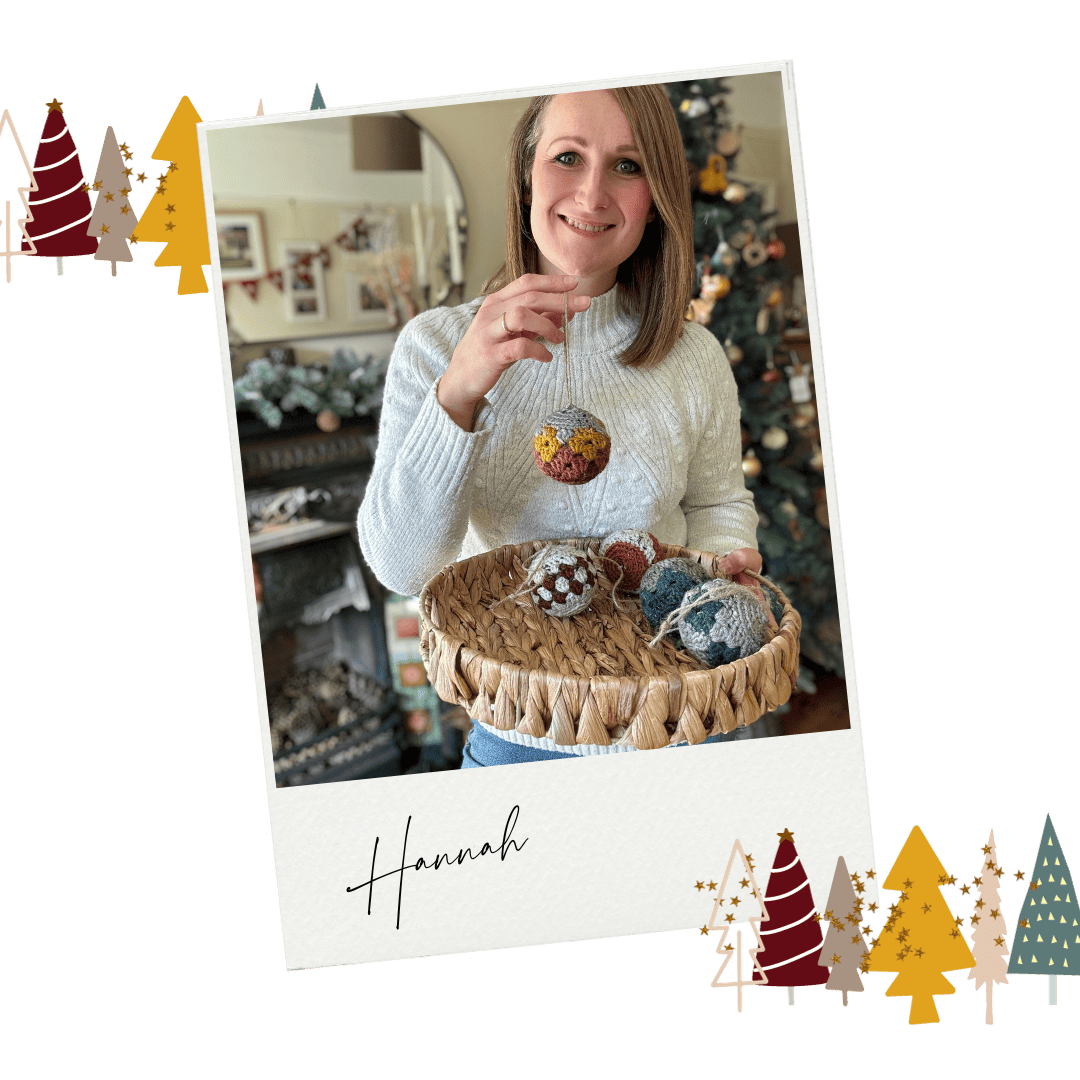 A woman holding a basket of ornaments in front of a christmas tree.