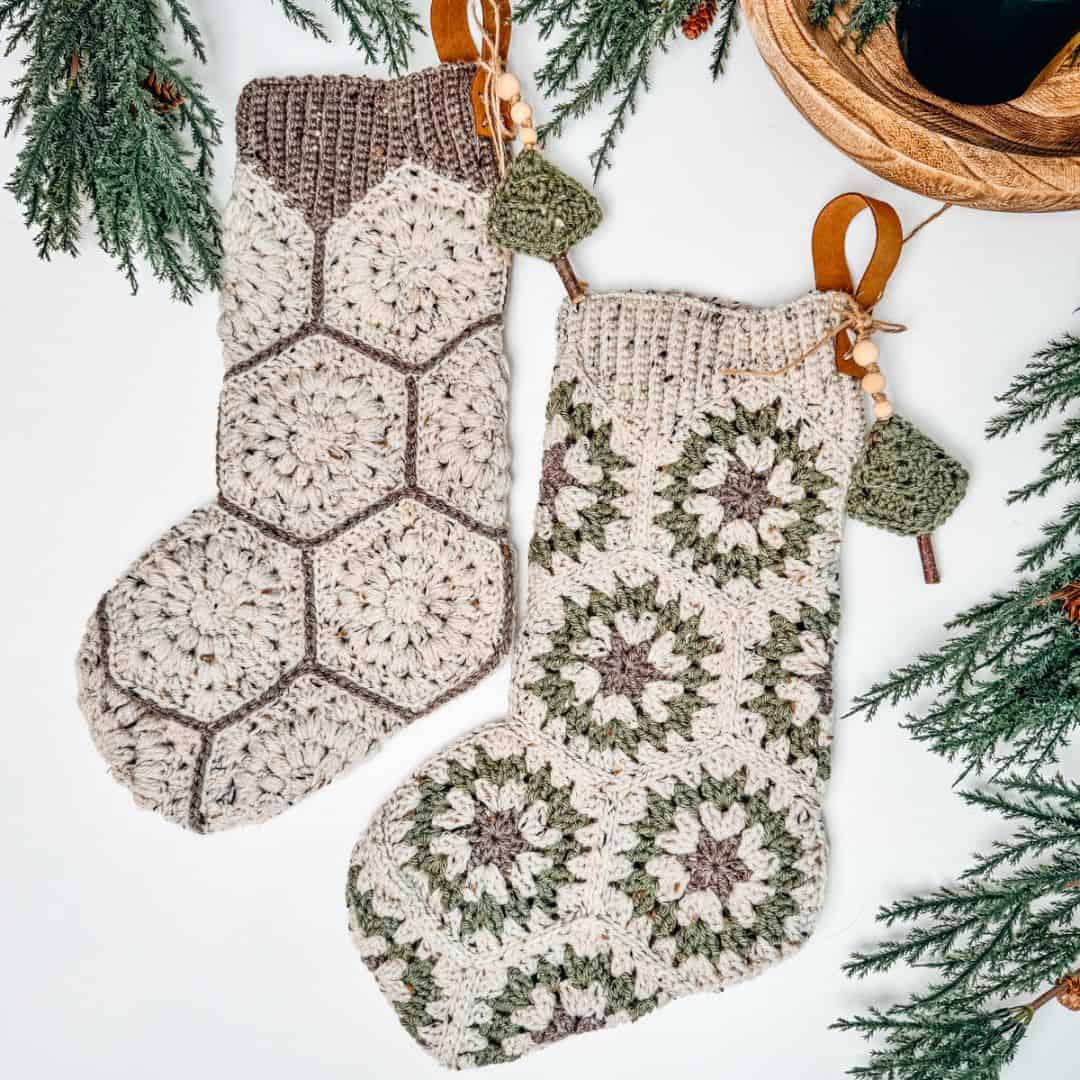 Two crocheted christmas stockings with pine cones and pine needles.
