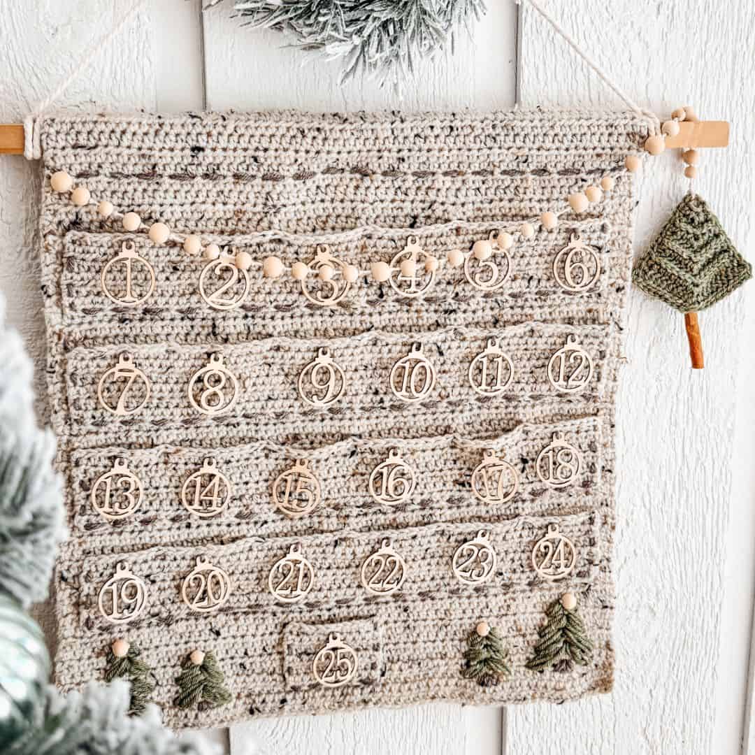 A crocheted advent calendar hanging on a wall.