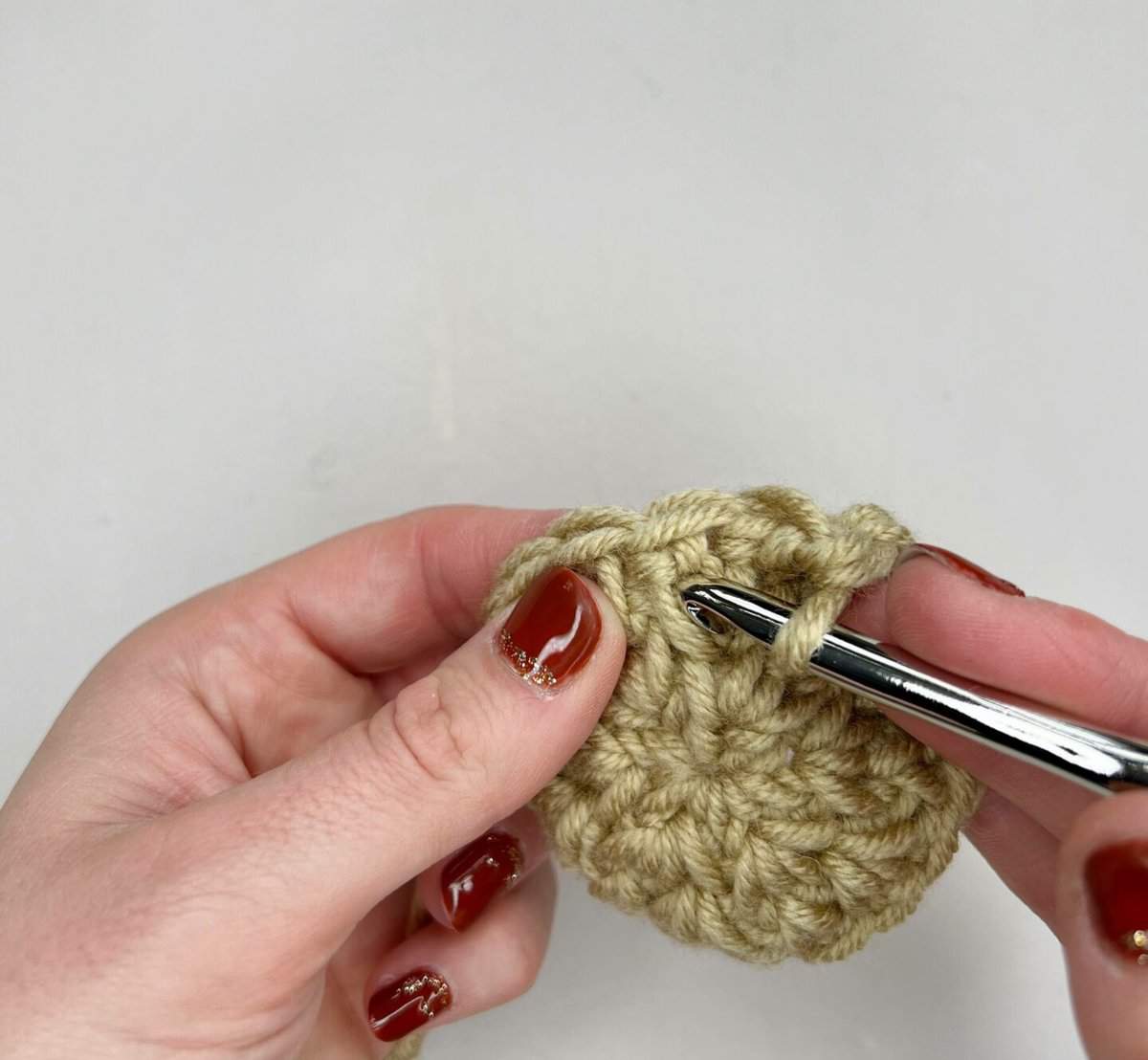 A person starting the split extended single crochet stitch by inserting the hook into the centre of the stitch.