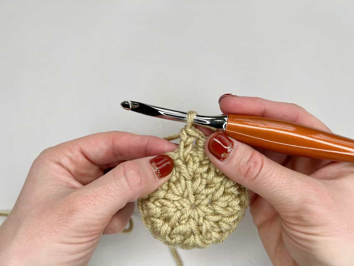 A person using a crochet hook to make  the split extended single crochet stitch - a completed stitch.