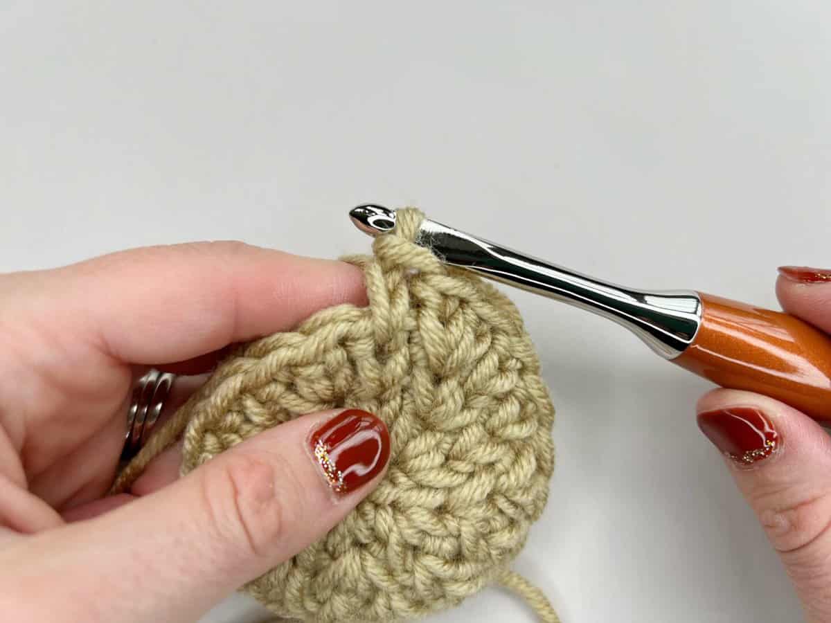 A person skillfully using a crochet hook to create a crocheted circle using the waistcoat crochet stitch (knit stitch).