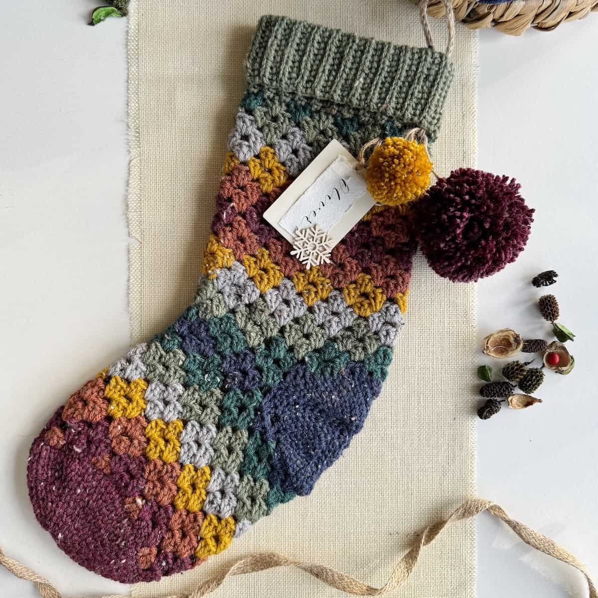 A crocheted christmas stocking with pom poms.