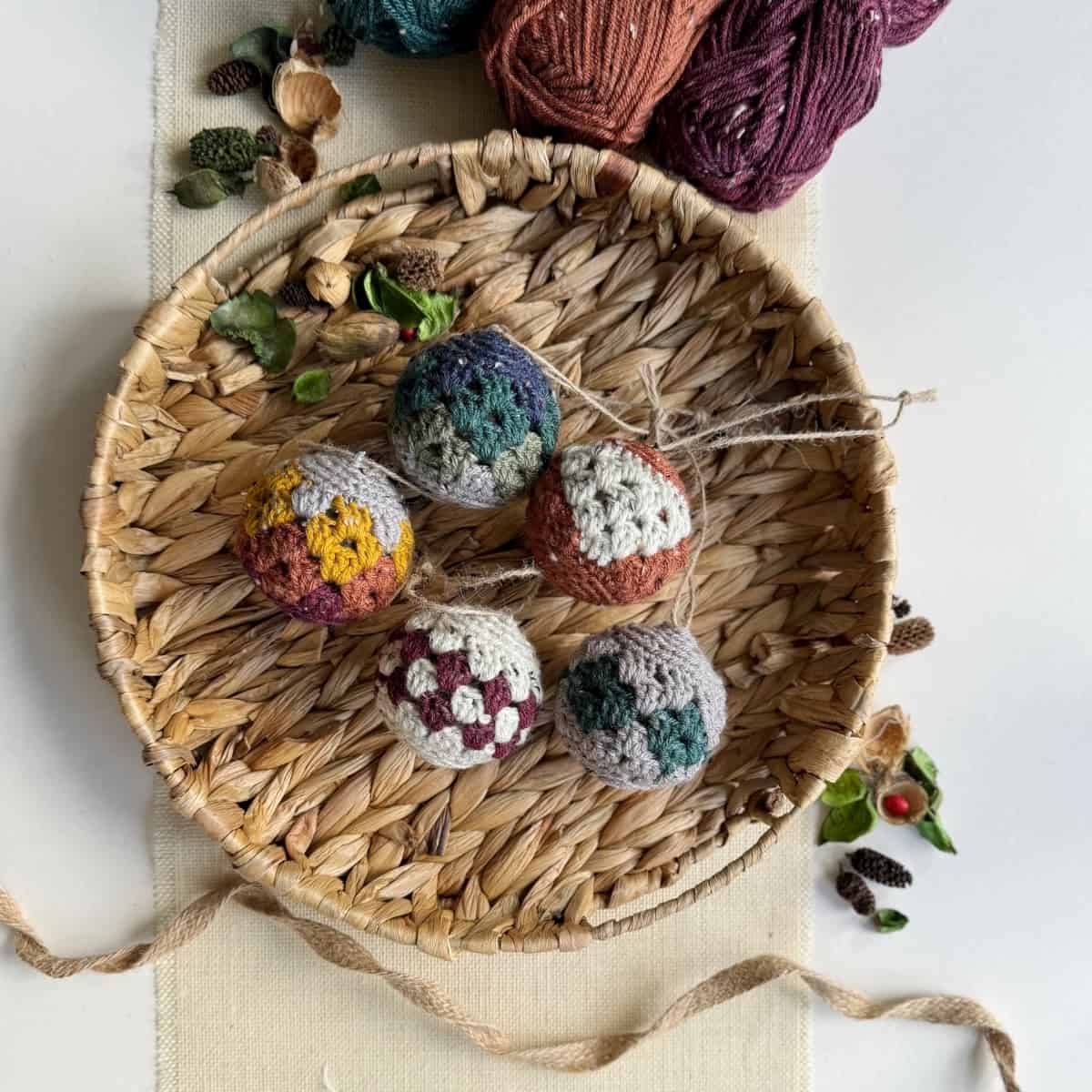 Crocheted ornaments in a basket on a table.