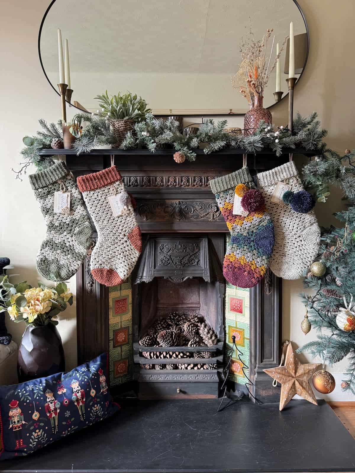 Multi colour crochet Christmas stockings on a mantle in front of a fireplace.