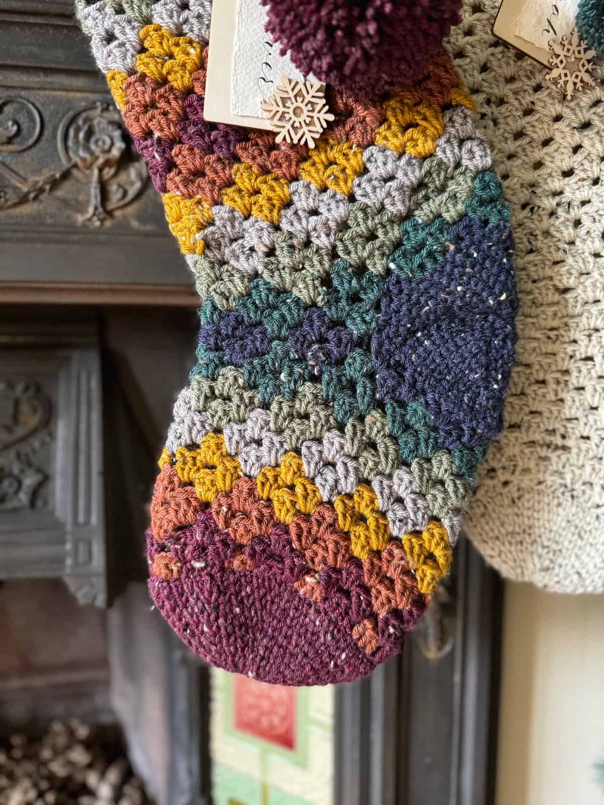 Two crocheted Christmas stockings hanging on a fireplace with a close up of the granny stitch in lots of colours.