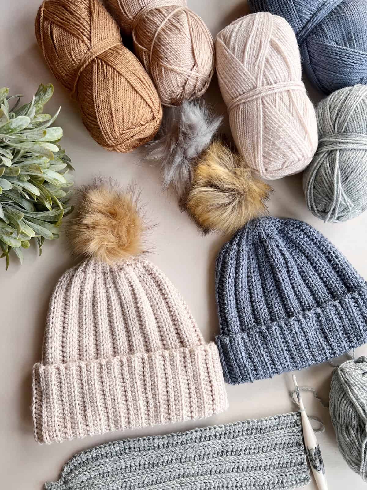 Hats, yarn, and knitting needles are laid out on a table.