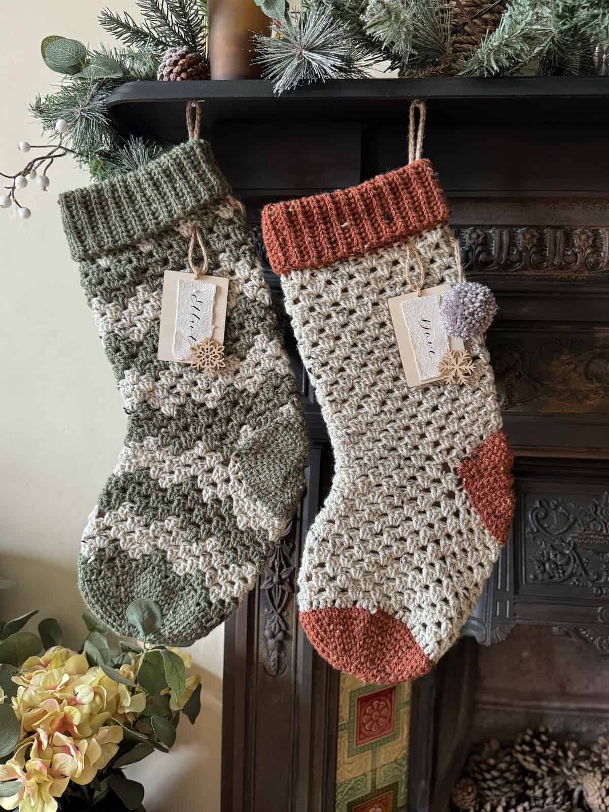 Two crochet Christmas stockings hanging on a fireplace.