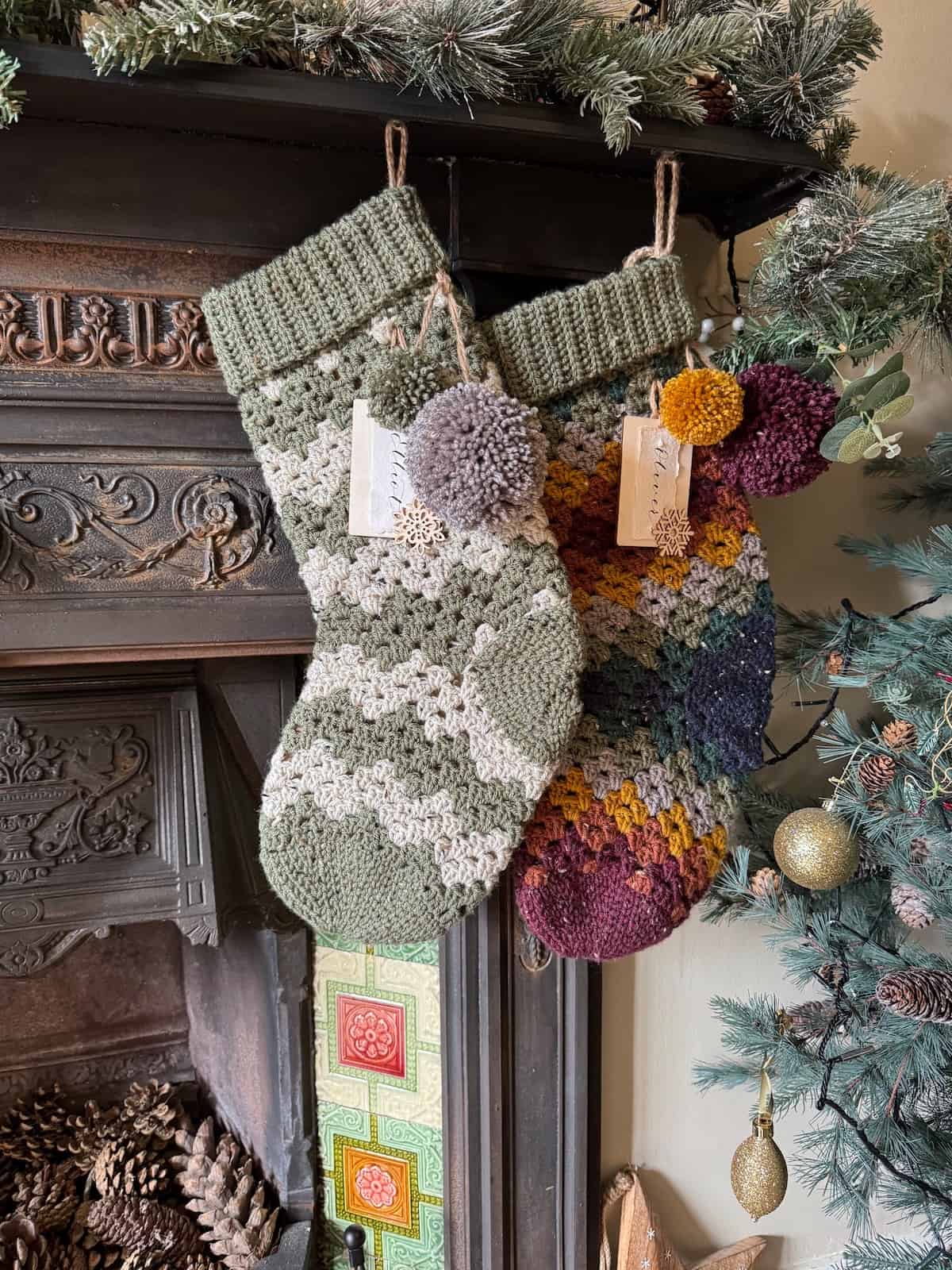 Two crochet Christmas stockings hanging on a fireplace.