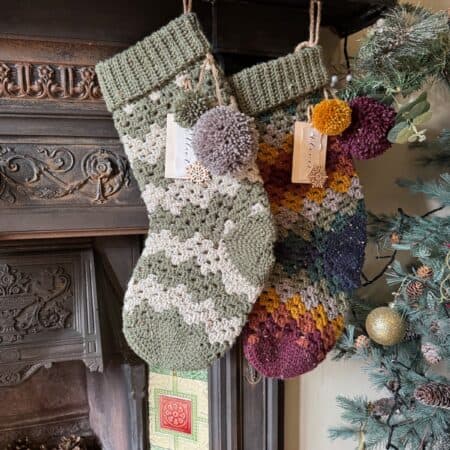 Two knitted christmas stockings hanging on a fireplace.