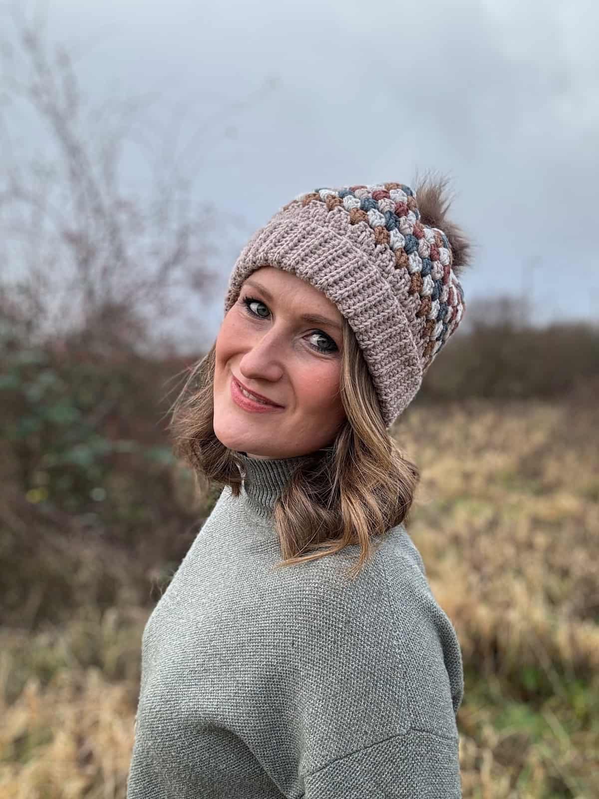 A woman wearing a knitted hat in a field.