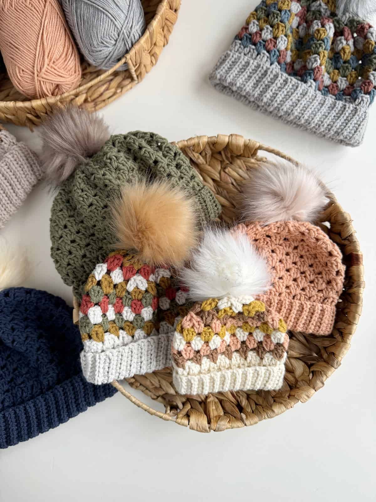 Crocheted hats with pom poms in a basket.