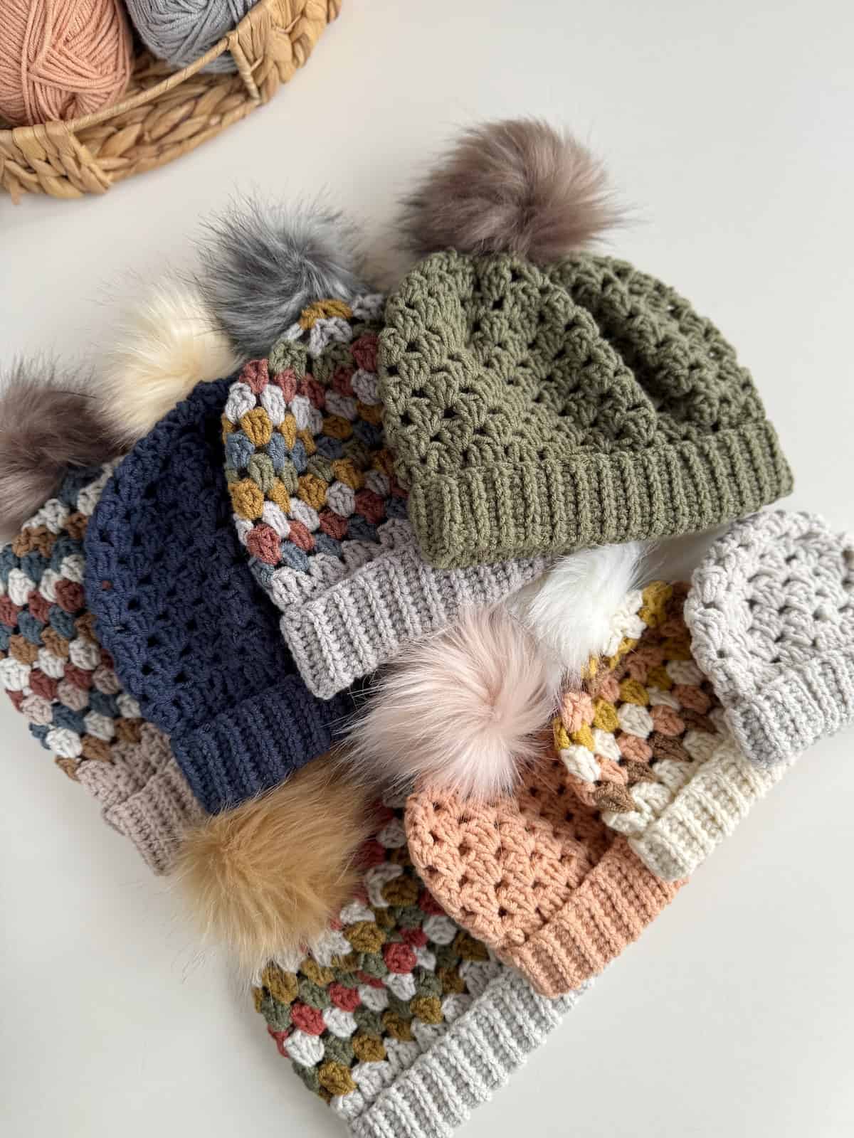 A group of crocheted hats with pom poms.