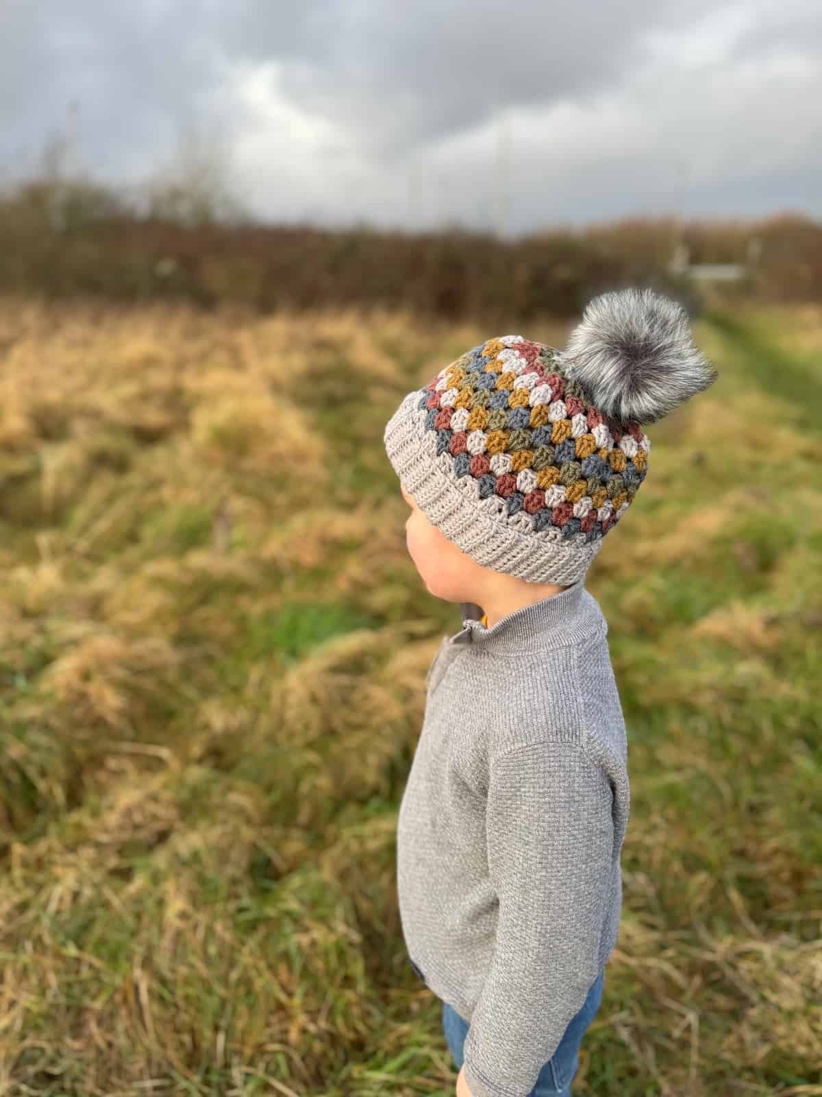 A young boy in a hat standing in a field.