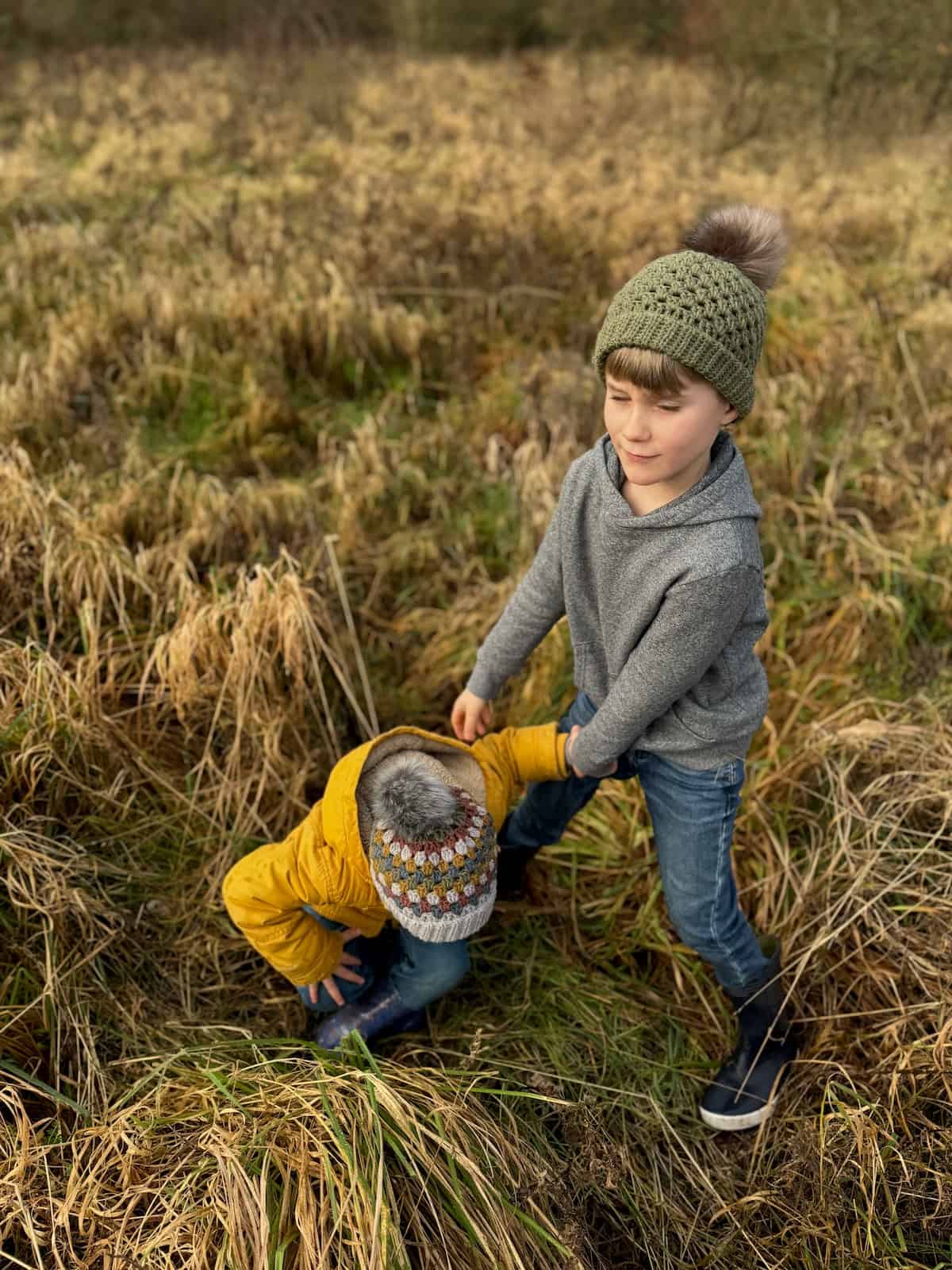 Two children playing in a field of tall grass.
