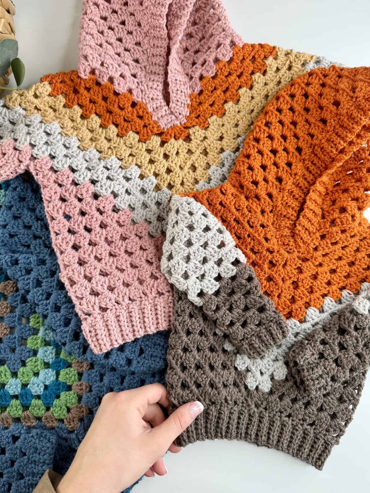 A hand holding a crocheted hoodie.