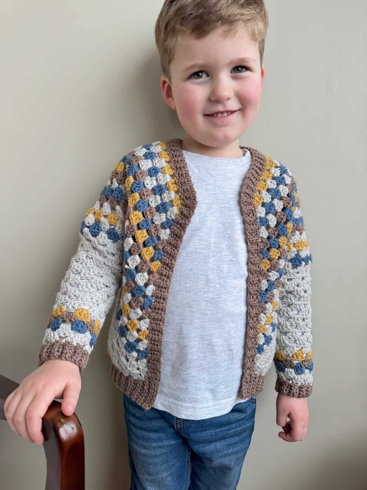 A young kid in a crochet cardigan.
