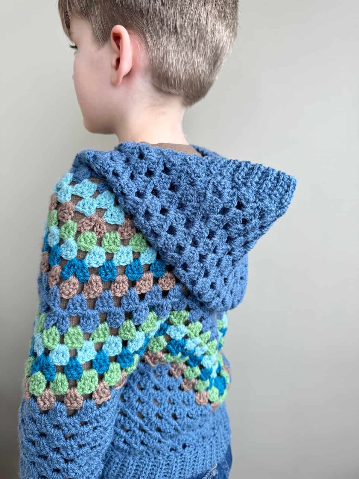 A young boy wearing a blue crocheted hoodie.