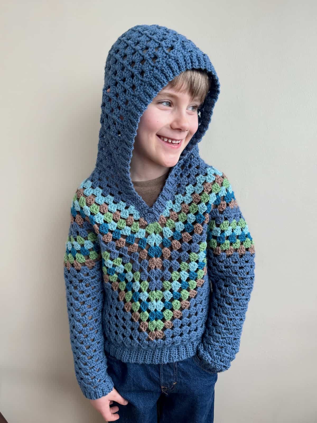 A young boy wearing a blue crocheted hoodie.