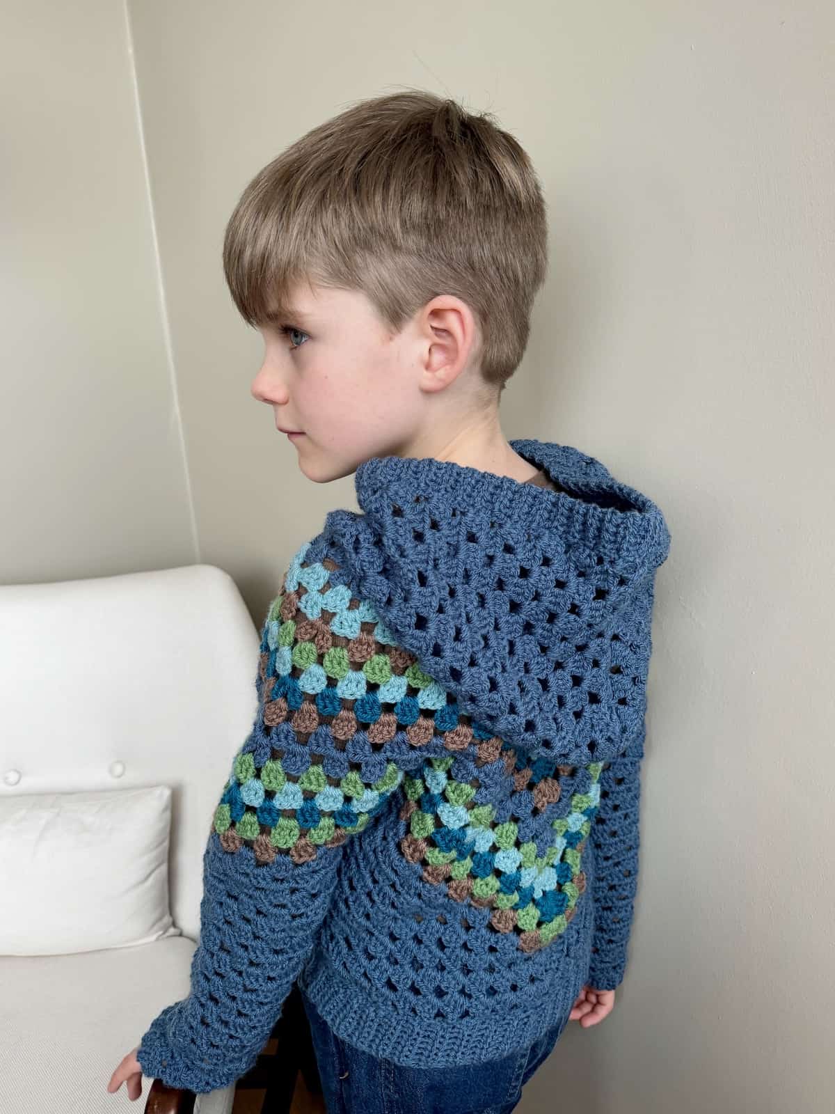 A young boy wearing a blue crocheted hoodie.