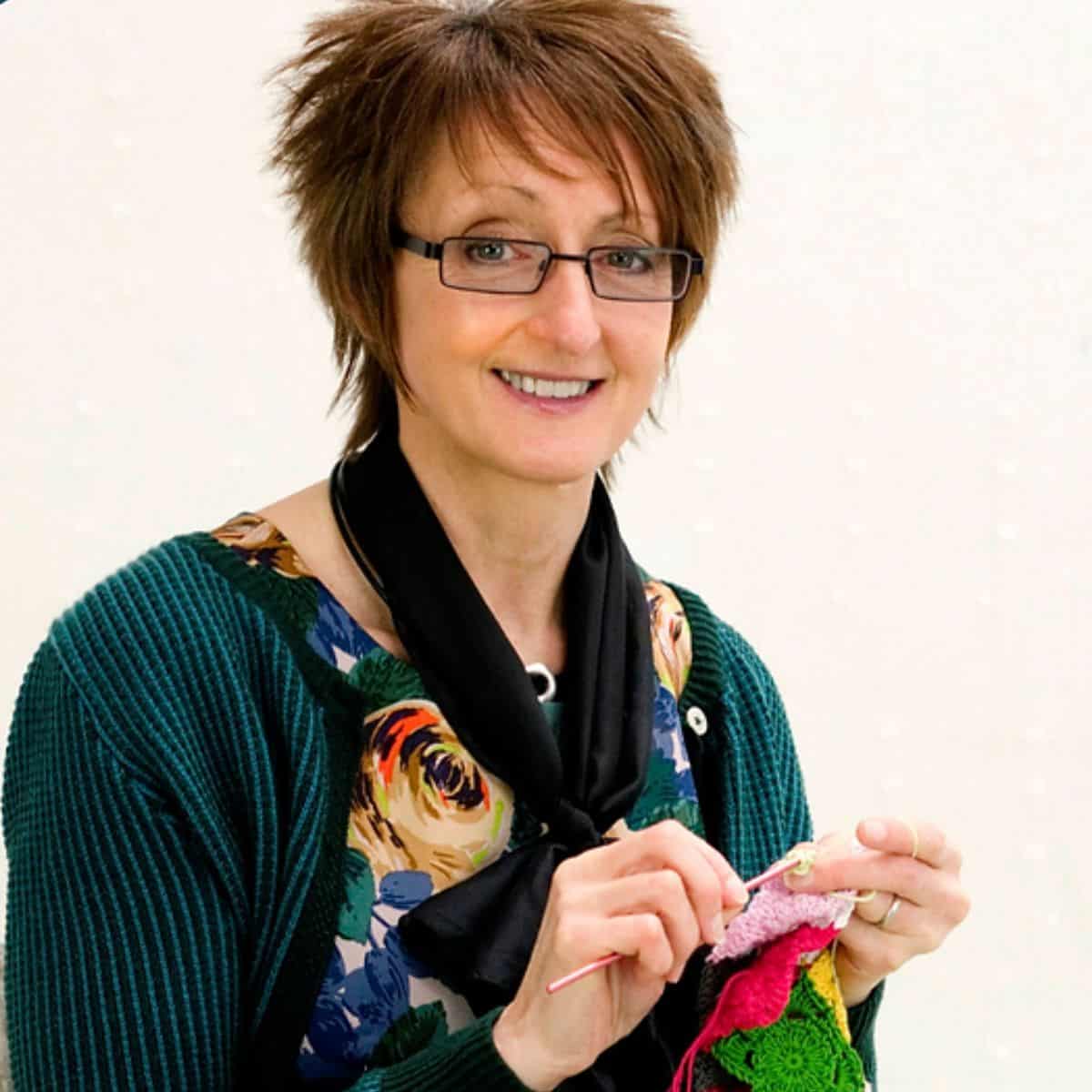 A woman holding a crocheted garment.