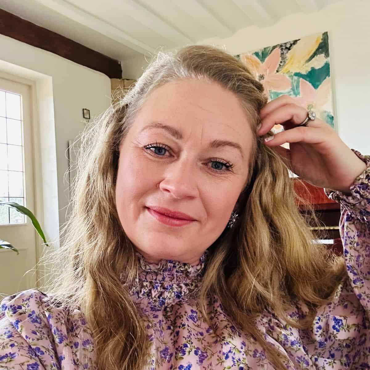 A woman in a crochet purple floral top posing for a summit photo.