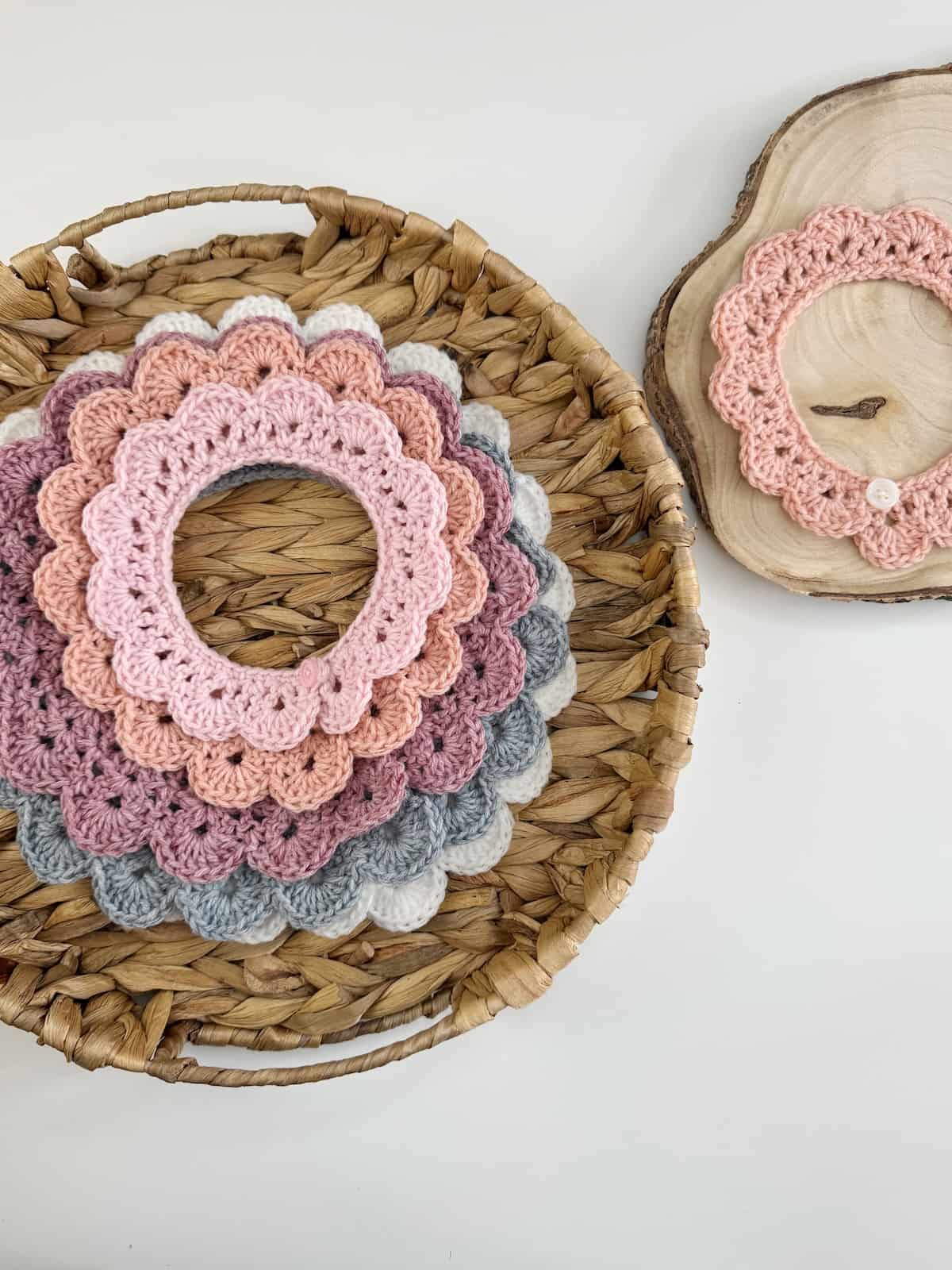 A pile of crocheted collars in a basket on top of a wooden table.