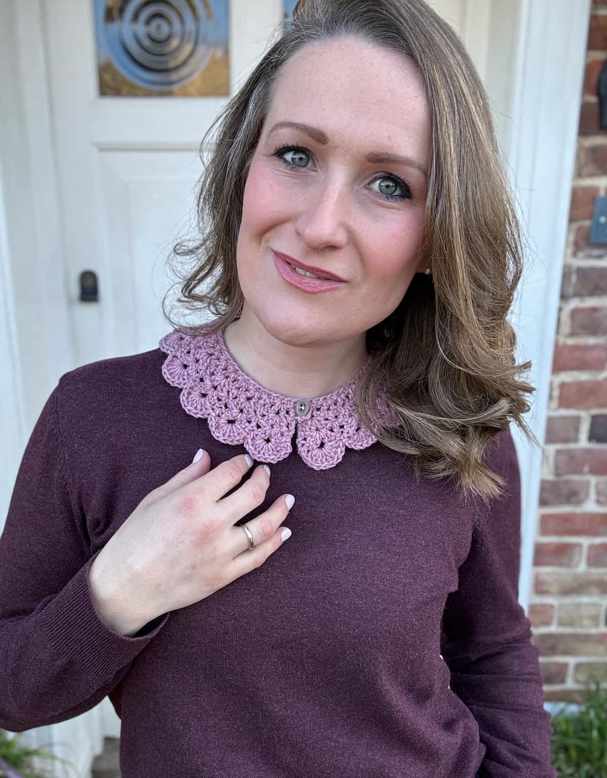 A woman wearing a burgundy sweater with a crochet collar.