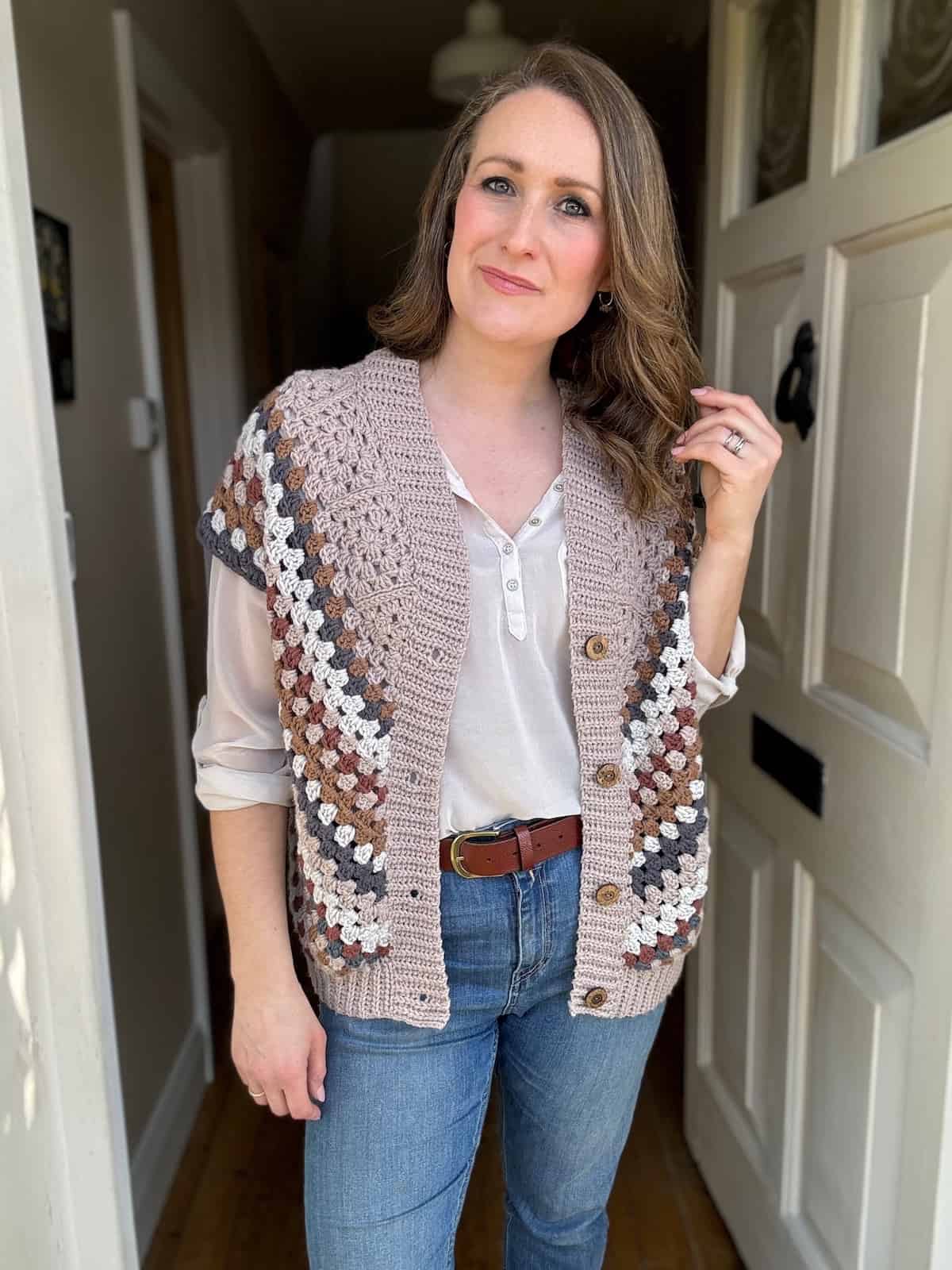 Woman in a retro crochet vest and jeans standing indoors.