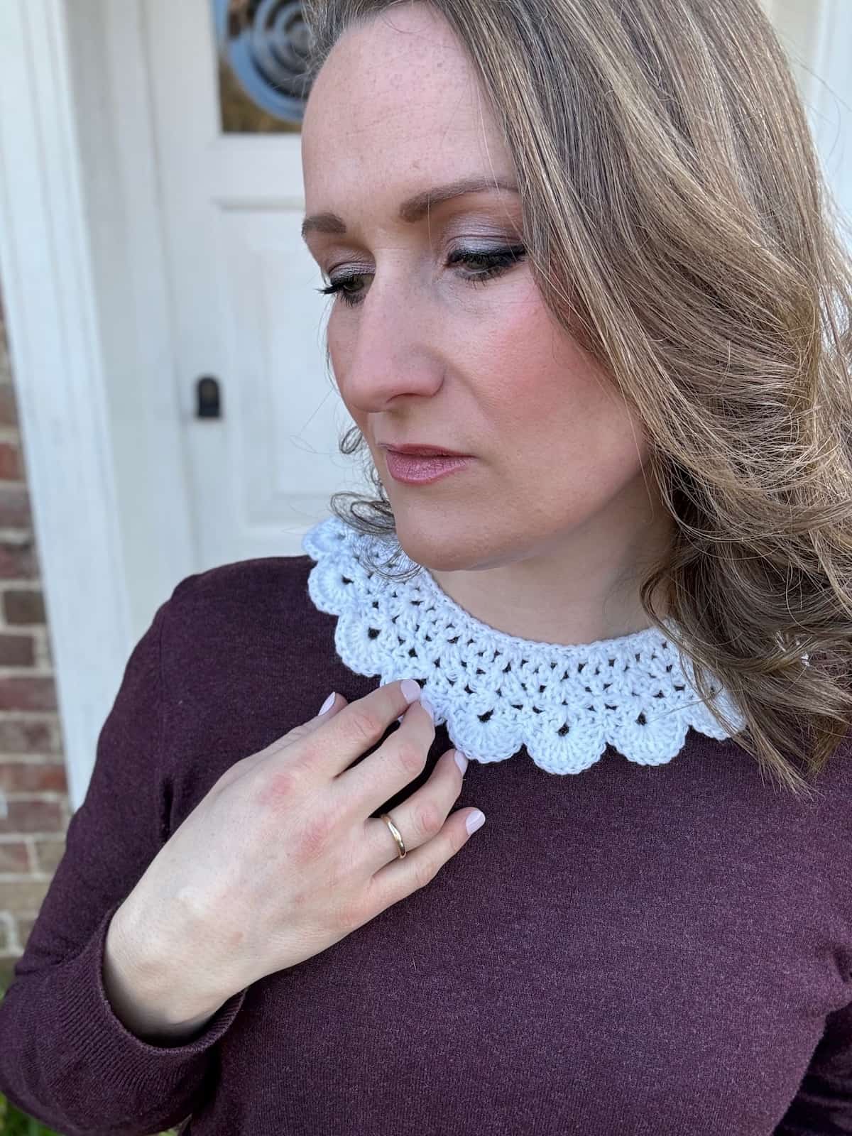 A woman wearing a burgundy sweater with a white lace collar.