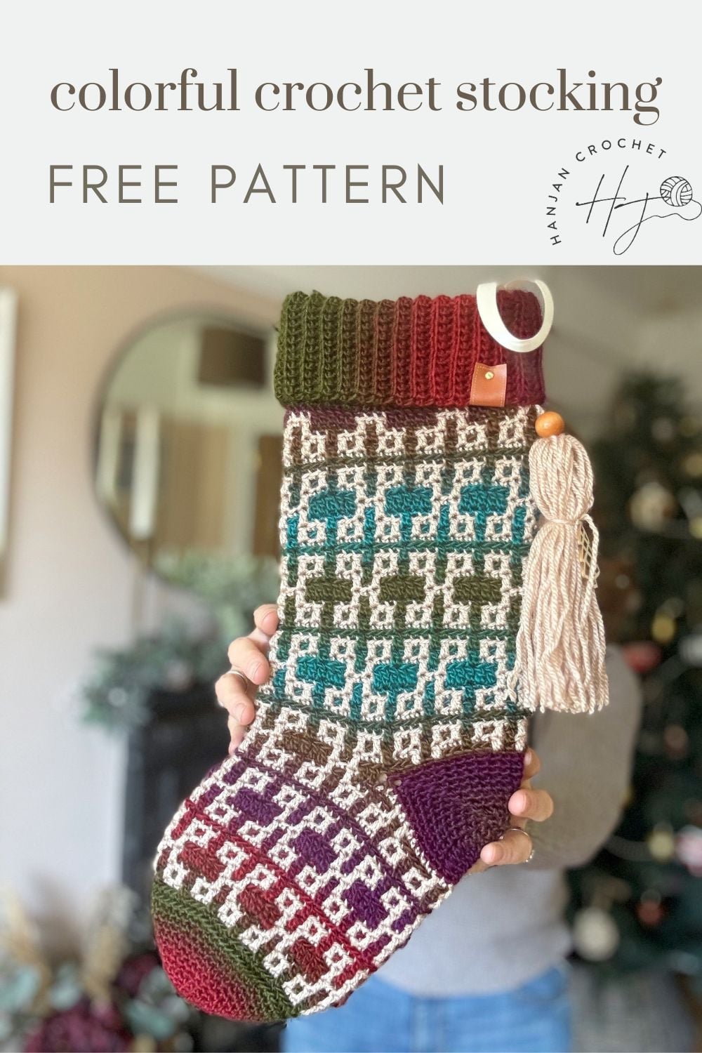 A hand holds a multicolored crochet stocking with geometric patterns and attached yarn skeins; text reads "colorful crochet Christmas stocking pattern FREE PATTERN.