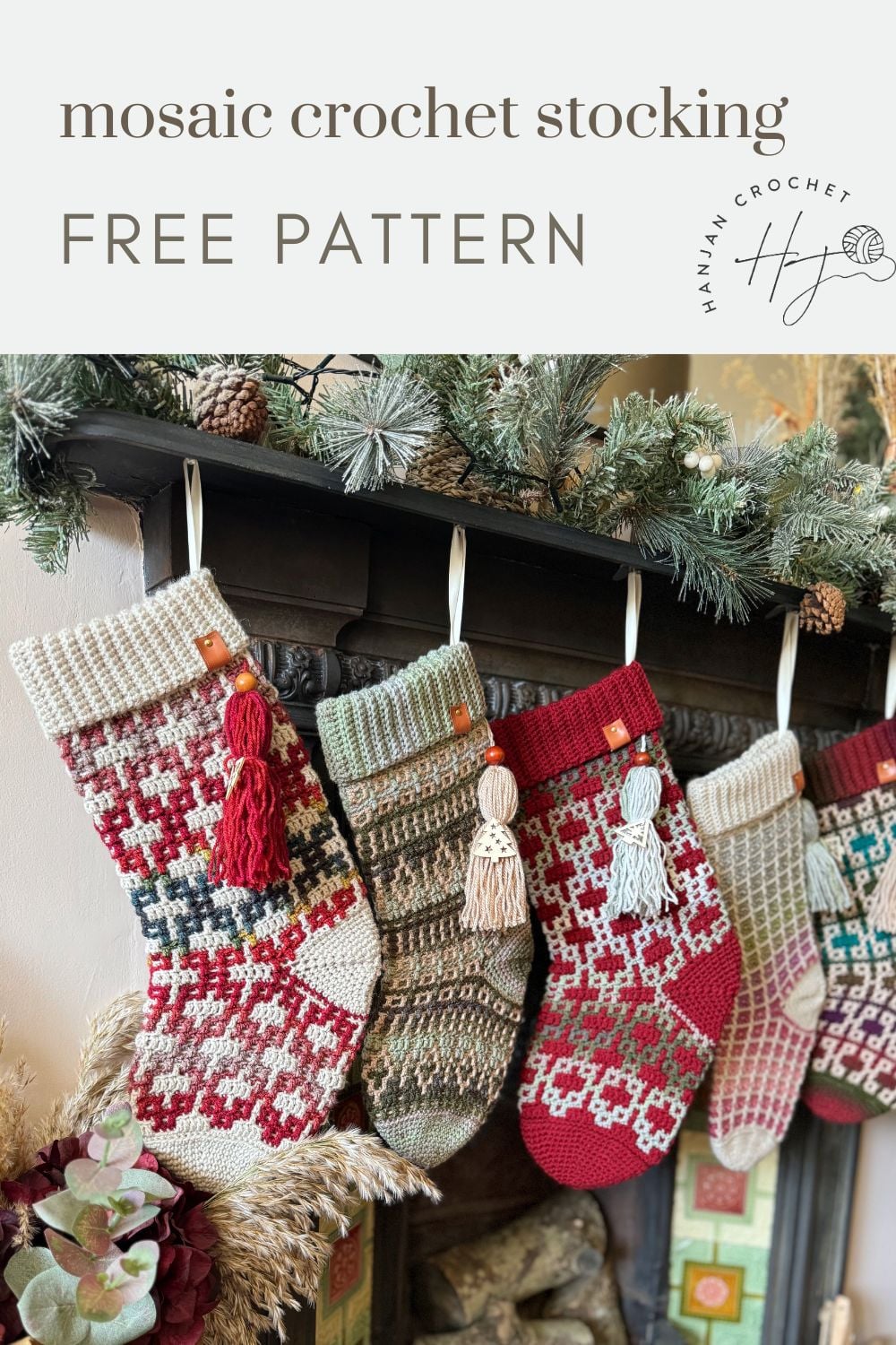 Four crocheted Christmas stockings with intricate patterns and tassels hang from a decorated mantel adorned with greenery and pine cones. Text above reads "mosaic crochet stocking FREE PATTERN." This charming display is perfect inspiration for anyone searching for a beautiful crochet Christmas stocking pattern.