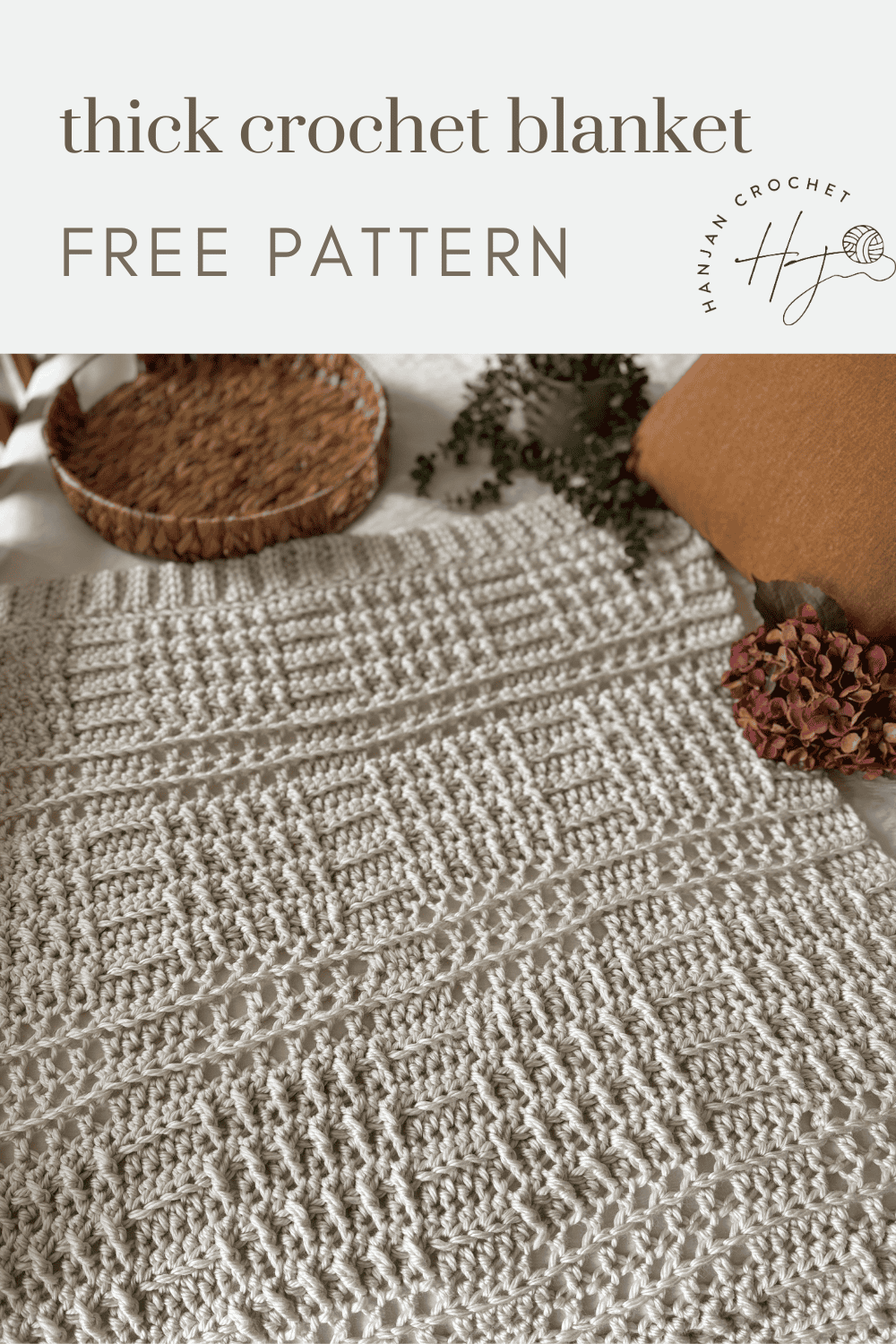 A thick, cream-colored crochet blanket with textured patterns is displayed on a bed, surrounded by pillows, a woven basket, and dried flowers. Text reads: "thick crochet blanket pattern FREE PATTERN.