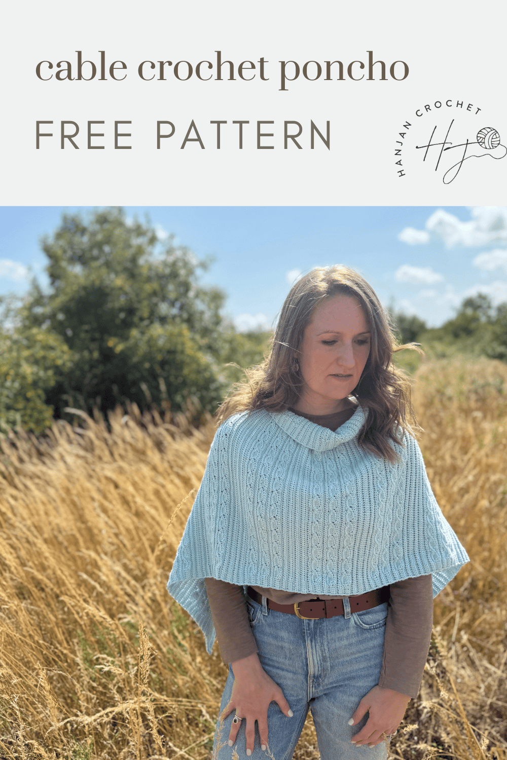 A woman stands in a field wearing a light blue crochet poncho over a beige long-sleeve top and jeans. Text above reads "cable crochet poncho" and highlights this stylish free crochet poncho pattern, perfect for your next cozy project.