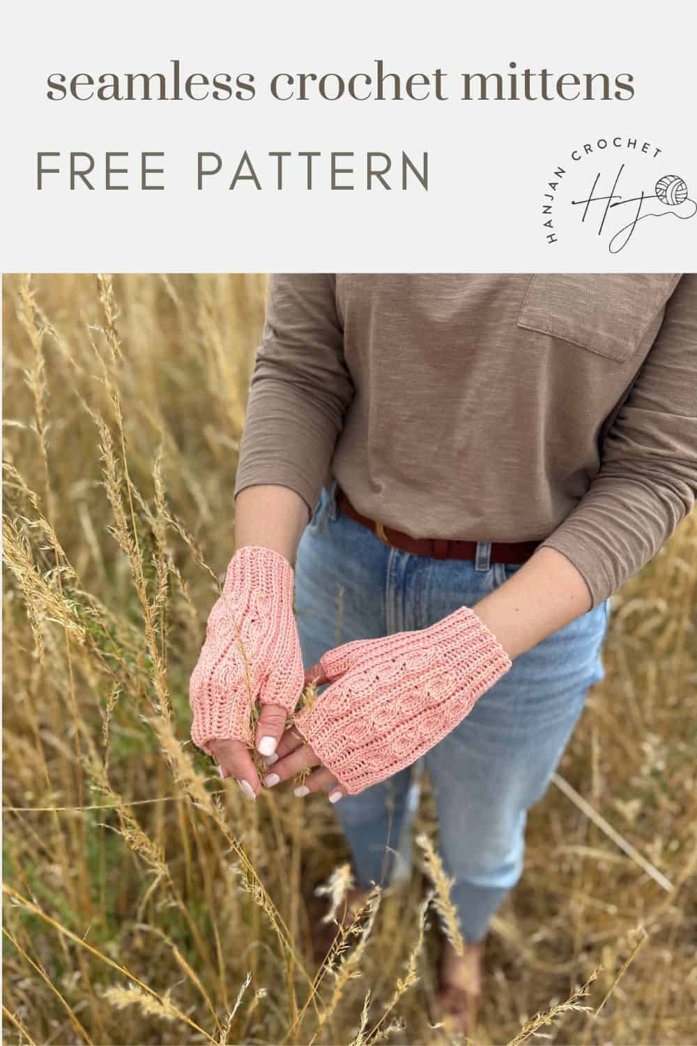 A person stands in a field wearing light pink, crocheted fingerless mittens with a cable pattern. Text above reads "crochet fingerless mittens pattern free—seamless and stylish!.