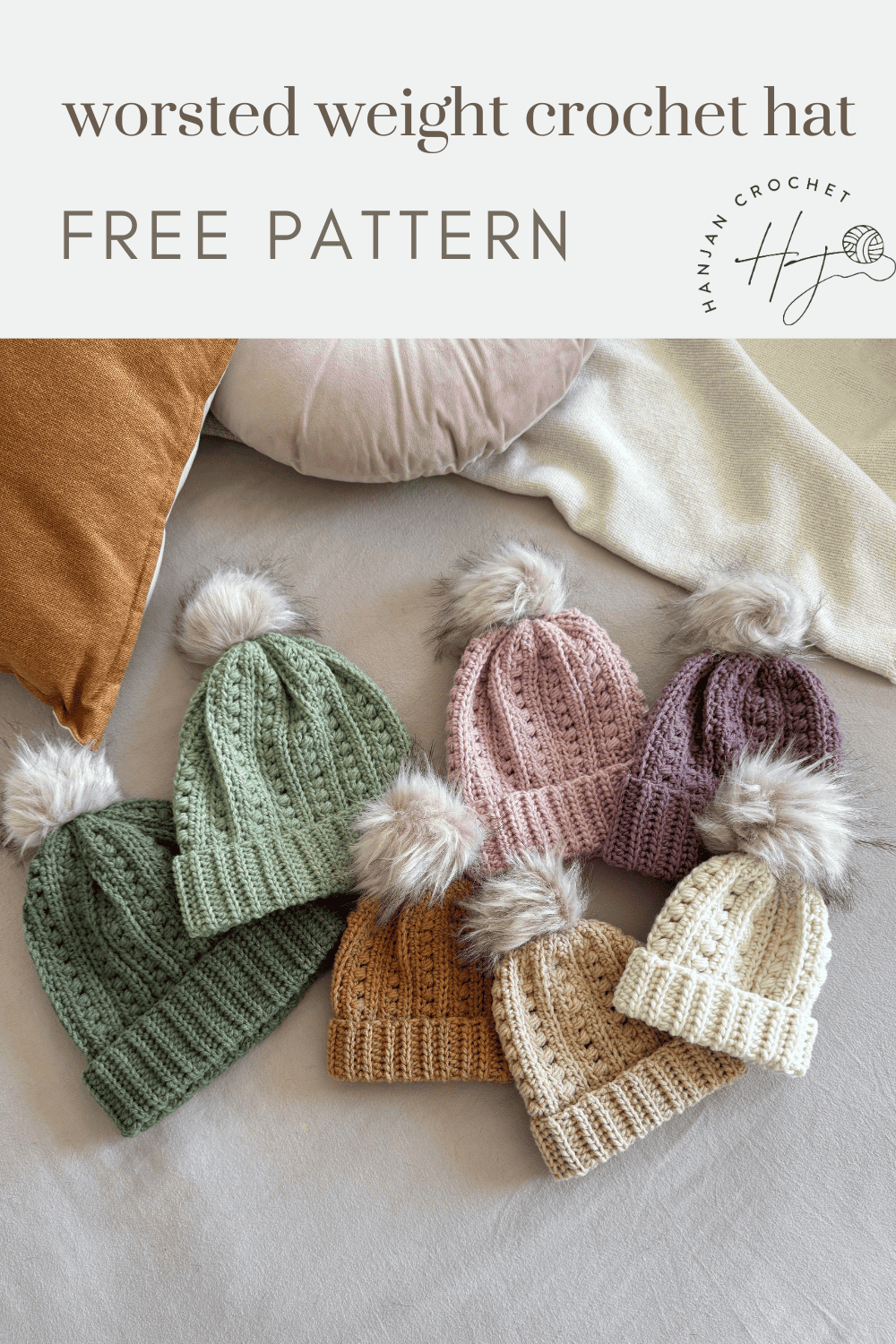 Six crocheted hats in various pastel colors with faux fur pom-poms are displayed on a bed next to pillows. Text reads: "worsted weight puff stitch crochet hat pattern FREE PATTERN.
