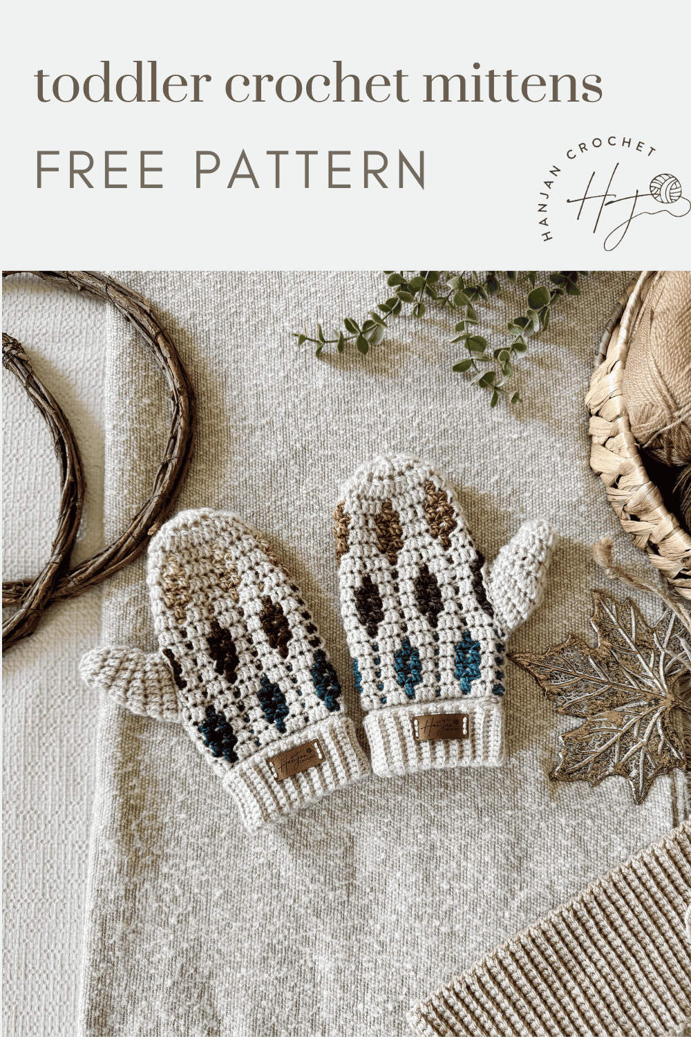 A pair of crocheted toddler mittens with multicolored accents is displayed on a textured fabric surface with decorative items nearby. Text reads "toddler mosaic crochet mittens pattern FREE PATTERN.