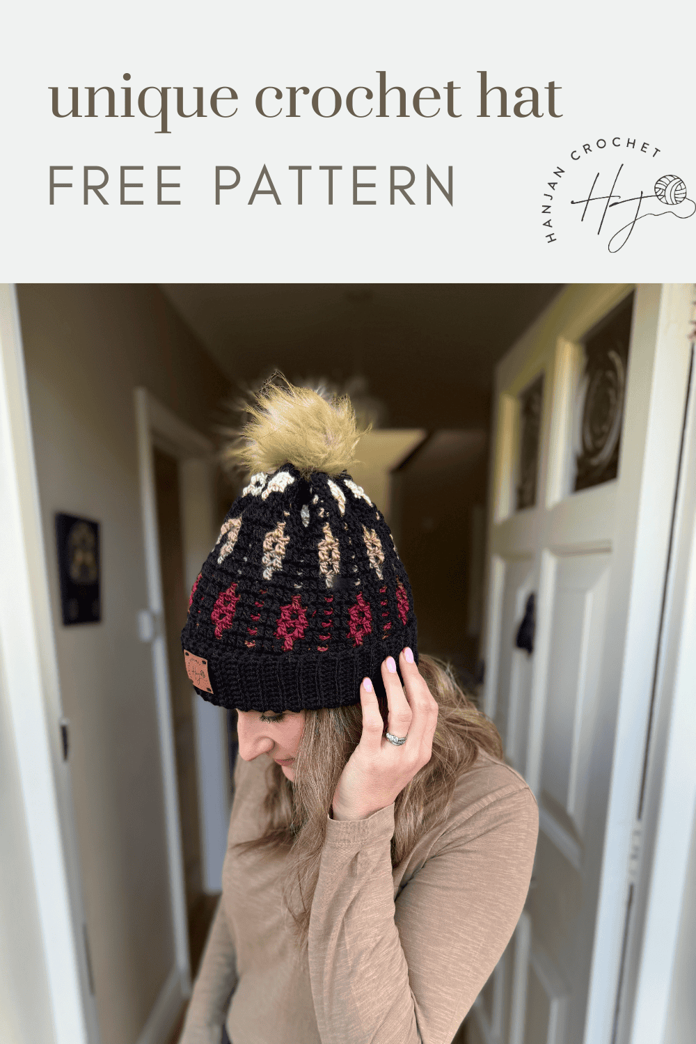 A woman wearing a black mosaic crochet beanie with a pom-pom stands in a hallway. Text above reads "unique crochet hat FREE PATTERN.