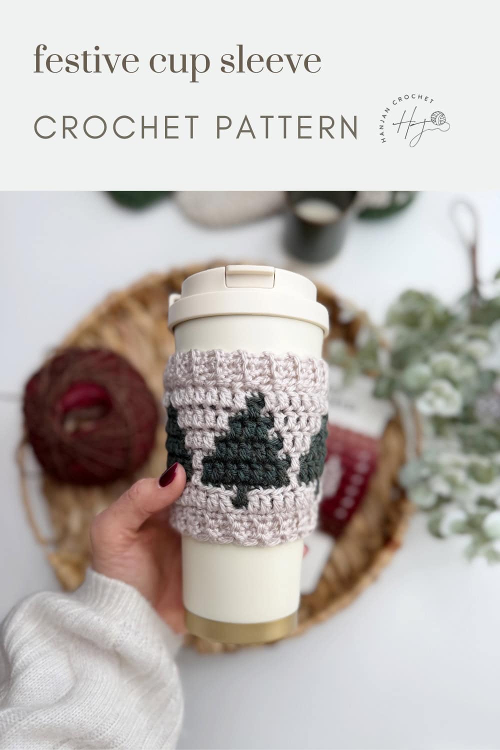 A hand holds a reusable cup with a crocheted sleeve featuring green tree shapes; text above reads "festive cup sleeve CROCHET COFFEE SLEEVE PATTERN.